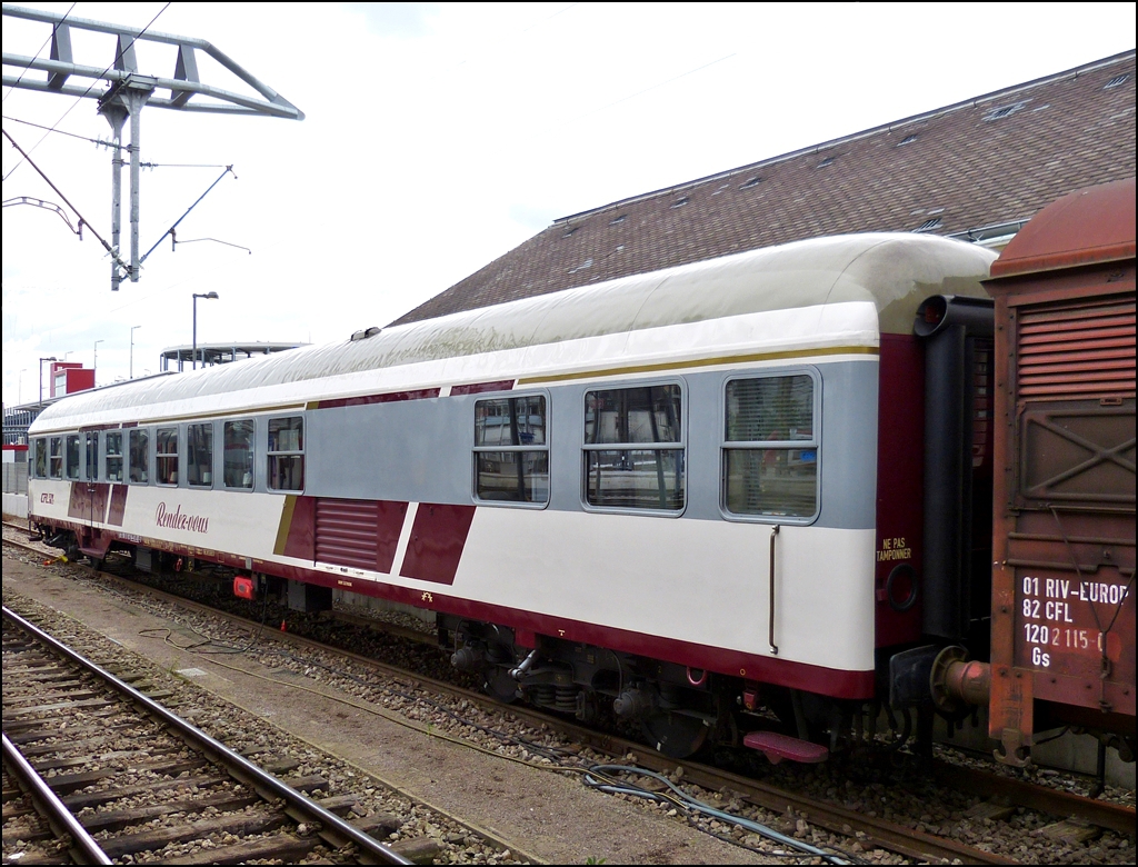 . Am 14.06.2013 konnte ich den neu gestylten Rendez-vous Wagen im Bahnhof von Luxemburg fotografieren. (Hans)

Ein kleiner Einblick in die Geschichte der Wegmann Wagen bzw. des Rendez-vous Wagens:

In den Jahren 1965 und 1967 beschaffte die CFL 60 Nahverkehrswagen bei der Firma Wegmann in Kassel. Diese Wagen  waren aus der Bauart Bnb-59 (sp�ter Bn 719) der Deutschen Bundesbahn abgeleitet worden. Die Ausf�hrung war den technischen Gegebenheiten auf dem luxemburgischen Streckennetz angepa�t worden. Dank ihrer universellen Ausstattung erreichten die Wagen im Planverkehr Ziele wie Li�ge, Amsterdam, Koblenz, Limburg (Lahn) sowie heute noch nach Blankenberge. Im Sonderverkehr wurden GAR Antreffen, K�ln, Hamburg, Bremerhaven, Berlin, Budapest, Salzburg, Innsbruck, Wien Brig, Chur, Chiasso und Dijon erreicht.

57 dieser Wagen wurden bei der CFL in Anbetracht der Zunahme der Zugleistungen um 40% zwischen 1990 und 1995 general�berholt. 2 Wagen waren zuerst abgestellt ehe sie dann in Fahrradwagen (Velos) umgebaut wurden.

Der 60. Wagen wurde einer neuen Bestimmung zugef�hrt: der RENDEZ-VOUS Wagen des G.A.R.

Seit seiner Gr�ndung im Jahre 1973 organisiert der GAR (Groupement des Amis du Rail asbl) Gruppenreisen f�r seine Mitglieder in enger Zusammenarbeit mit der CFL. Um den stets wachsenden Anspr�chen der Teilnehmer gerecht zu werden, wurde das Verpflegungssystem immer mehr ausgebaut. Gab es anfangs lediglich kalte Getr�nke, so konnten ab 1979 Kaffee und Croissants, ab 1980 belegte Br�tchen und ab 1981 komplette Mahlzeiten angeboten werden.

1986 anl��lich der Fahrt des Sonderzuges  Carolus Magnus  nach Aachen (dem Luxemburger Volke wurde damals der Karlspreis verliehen), wurde erstmals ein Wegmann behelfsm��ig mit auf den Wagen zugeschnittenen Tischen eingerichtet. Diese Einrichtung sollte ab diesem Zeitpunkt bei Sonderz�gen den Fahrg�sten eine Entspannungsm�glichkeit bieten; mit der entsprechenden Ausstattung erhielt der jeweilige Wagen den Namen  Rendez-Vous . Ein Konzept war geboren.

Ab 1987 fand planm��ig ein  Rendez-Vous  Wagen Eingang in die Zugbildung des Blankenberge Expre�.

Da die Montage und Demontage der gesamten Ausr�stung (18 Tische, sowie eine K�cheneinrichtung) vor und nach jeder Fahrt doch aufwendig war, stellte die CFL ab 1990 f�r die Saison einen Wagen ganzzeitig zur Verf�gung. Das System kannte einen sehr gro�en Erfolg und heute sind Sonderfahrten ohne das  Rendez-Vous  kaum mehr vorstellbar. Es soll hier bemerkt werden, da� alle Mitglieder des GAR diese Arbeiten ehrenamtlich verrichten.

Als Ende 1994 die Generalsanierung des entsprechenden Wagens f�llig war. entschlo� sich die CFL, fortan einen Wagen f�r diese Sondereins�tze zu spezialisieren. Die Zusammenarbeit CFL/GAR f�r den neuen  Rendez-Vous  Wagen konnte beginnen.

Um den zuk�nftigen Unterhalt rationell zu gestalten, wurde von Anfang an festgehalten, da� ein Wegmann Wagen der CFL die g�nstigste Ausgangsm�glichkeit f�r den Umbau bieten w�rde.

Die Ausf�hrung der Arbeiten wurde der CFL Werkst�tte Petingen �bertragen, die elektrische Ausr�stung dem Personal der Werkst�tte Luxemburg anvertraut. Der GAR hatte alle  Rendez-Vous  spezifischen teile zu besorgen (K�che, Gep�ckablagen, Bez�ge der Sitze, …)

Folgende wichtige Umbauten waren vorzunehmen:
- Einrichtung einer gro�en und funktionellen K�che mit Gasherd unter gleichzeitiger Stillegung einer der beiden fr�heren Einstiegsplattformen.
- Stromversorgung sowohl �ber die klassische Lichtmaschine als auch (Wahlweise) durch ein 6,5 kW Dieselaggregat und entsprechende Anpassungen an den elektrischen Schaltkreisen.
- Optimale thermische und akustische Isolierung des Wagens.
- Anpassung des Heizungssystems.
- Verlegen eines speziellen rutschhemmenden Bodens.
- Einbau fester Tische zwischen den Sitzen mit Befestigung an der Seitenwand und Abst�tzung auf einem Bein am Boden.
- Zus�tzliche Beleuchtung (umschaltbar) durch elektrische Tischlampen.
- Beziehen der Sitze mit Stoff.
- Umbau der Sitze und Ver�nderung der Inneneinrichtung durch den Einbau von L�ngsgep�cktr�gern.
- Einrichtung einer Garderobe f�r die Mannschaft.
- Lackierung in einer besonderen, aber dennoch dem derzeit g�ltigen CFL Design entsprechenden   Form.
- F�r die W�nde wurden feuerfeste Platten in dunkelroter Farbe sowie rostfreier Stahl im K�chenbereich verwendet.

Es stehen maximal 66 Sitzpl�tze zur Verf�gung. Der Wagen kann mit einer H�chstgeschwindigkeit von 140 km/h in Belgien, D�nemark, Deutschland, Frankreich, Holland, Italien, �sterreich und der Schweiz eingesetzt werden.

Ende 2005 sind der Rendez-Vous Wagen sowie weitere 7 Wegmann Wagen vom Luxemburger Staat (Kulturministerium / Amt f�r Denkmalschutz) als historisch wertvoll klassiert worden. Die Wagen sind aber weiterhin im Besitz der CFL. Nachdem die Revisionsfristen 2010 abgelaufen waren wurde der Wagen abgestellt.

Anfang 2012 wurden der Rendez-Vous BR457 nach Neum�nster �berf�hrt. Der BR457 erhielt eine komplette Revision mit einem Neuanstrich.
