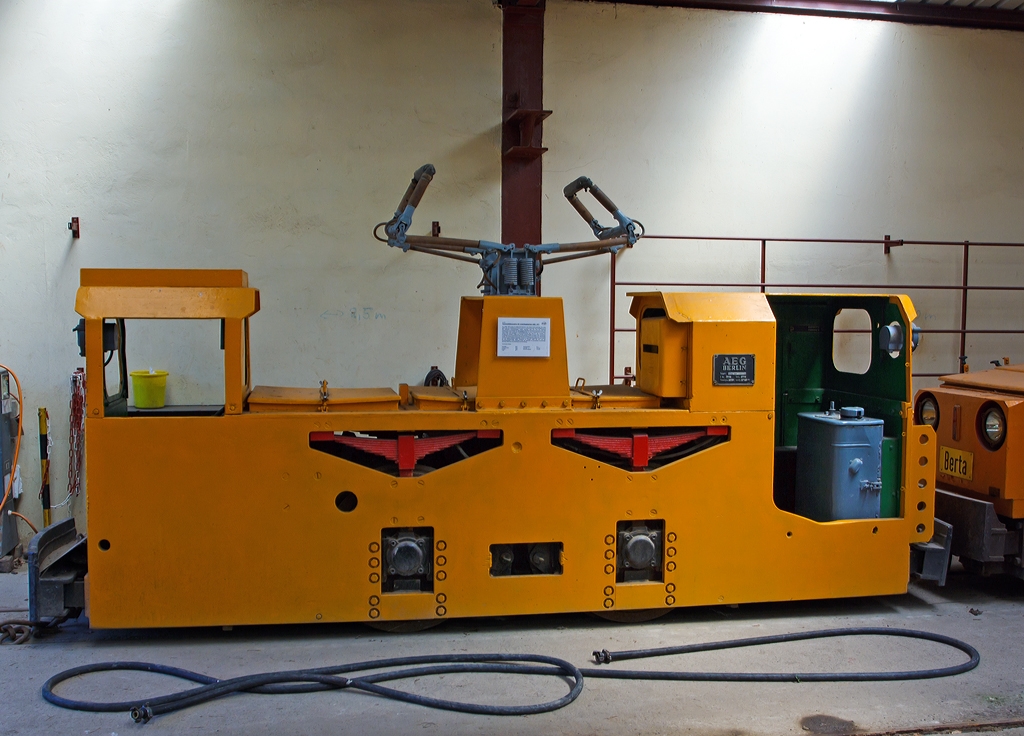 Die AEG Fahrdrahtlokomotive f�r Untertagebetrieb HF 1 (FGF Lok 61) von dem FGF (Feld- und Grubenbahnmuseum Fortuna, Solms-Oberbiel), am 07.07.2013 bei dem FGF im Lokschuppen.

Am 4.M�rz 1983 wurde zum letzten Mal Eisenerz in der Grube Fortuna gef�rdert. Vier Jahre sp�ter kam mit Schlie�ung der Grube Leonie in Auerbach/Oberpfalz (Bayern) das endg�ltige Aus f�r den deutschen Eisenerzbergbau. Dieses Bergwerk hatte erst 1978 die F�rderung aufgenommen und belieferte die nahe gelegene Maxh�tte (Sulzbach-Rosenberg) mit Erz. 
Die hochmoderne Grube besa� aus Rentabilit�tsgr�nden nur eine F�rdersohle bei 185 Metern Teufe (Tiefe). Dort besorgten 6 Gruben-Fahrdrahtlokomotiven des Typs HF1 den Transport der Erzz�ge zum Schacht. Wegen der enormen Wasserzufl�sse und der damit verbundenen Pumpkosten und Konkurrenzdruck des Auslandserzes mu�te der Betrieb 1987 geschlossen werden.

Die im Jahre 1962 hergestellte Lok war zun�chst auf der Schachtanlage Maffei (Nitzlbuch) im Einsatz, bevor sie 1977 auf das Anschlu�bergwerk Leonie umgesetzt wurde. 

Technische Daten:
Hersteller:  AEG
Fabriknummer:  8144
Baujahr:  1962
Type:  HF 1
Bauart:  Bo-e
Leistung:  50 kW (2x25)
Dienstgewicht:  8,0 t
L�nge �ber alles:  4.500 mm
Breite:  920 mm
H�he:  1.670 mm
Achsstand:  1.100 mm

Die Maschine ist grunds�tzlich betriebsf�hig, allerdings fehlt bisher die elektrische Fahrdrahtleitung. 
