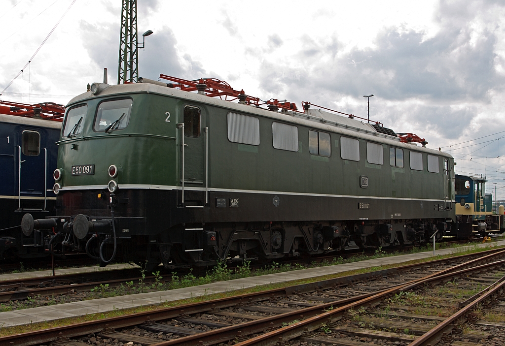 
Die schwere G�terzug-Elektrolokomotive E50 091 / 150 091-7 am 18.07.2012 im DB Museum Koblenz, in der Urspungsausf�hrung. 
Diese Lok wurde 1963 bei Krupp unter der Fabriknummer 4432 gebaut, der Elektrische Teil von AEG.
Die ab 1957 gebaute E 50 (ab 1968 als Baureihe 150 gef�hrt) war die erste schwere G�terzug-Ellok des Einheitslokomotivprogramms. Bis 1973 wurden in mehreren Serien insgesamt 194 Lokomotiven geliefert, die zun�chst die gleichen Aufgaben wie die schweren Lokomotiven der Baureihe E 94 vor dem Zweiten Weltkrieg �bernahmen und diese sp�ter ersetzten. Wie alle Lokomotiven des Einheitslokomotivprogramms hatte die Baureihe E 50 bzw. die sp�tere 150 Drehgestelle als geschwei�te Kasten-Konstruktionen mit Drehzapfen und geschwei�te Kastenaufbauten mit L�ftergittern.