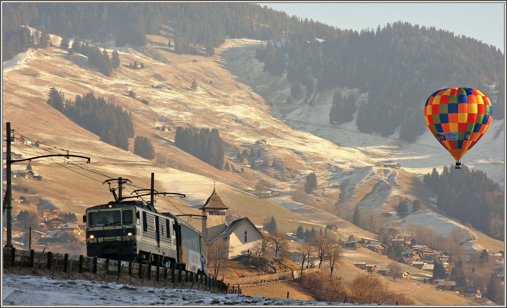 Ein Ballon setzt farbige Akzente als ein Goldenpass-Panoramiczug in Richtung Montreux Ch�teau d'Oex verl�sst.
(23.01.2011)