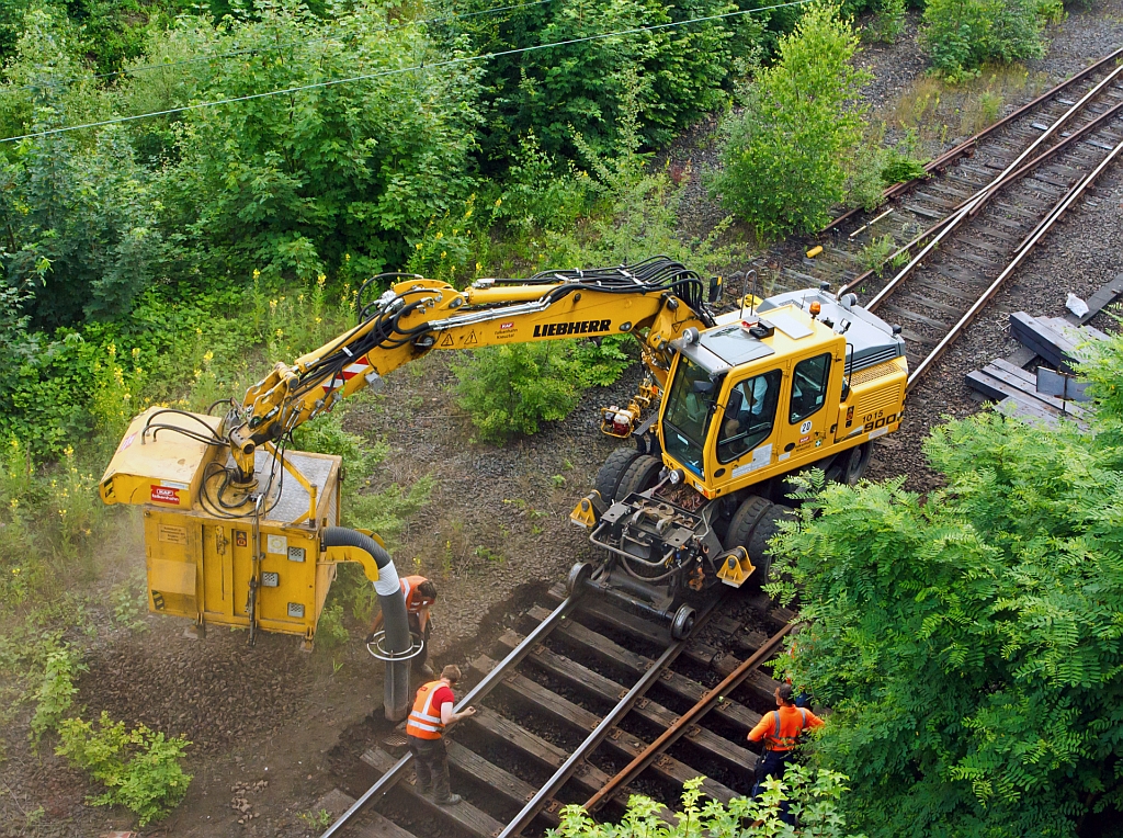 
Wie einfach man Schotter zwischen den Schwellen heraus bekommt - Mit Saugbagger  Saugstar   an Liebherr Mobilbagger A 900 C ZW der KAF Falkenhahn (Kreuztal) am 05.07.2012 in Betzdorf (Sieg) im Einsatz. Das Anbaugerät fast 1 qm Aushub bzw. Schotter, wenn es gefüllt ist, schwenkt der Bagger es über die Abladestelle (neben den Gleis, auf LKW oder Wagon). Dann wird die Bodenklappe hydraulisch geöffnet und der Aushub fällt heraus.