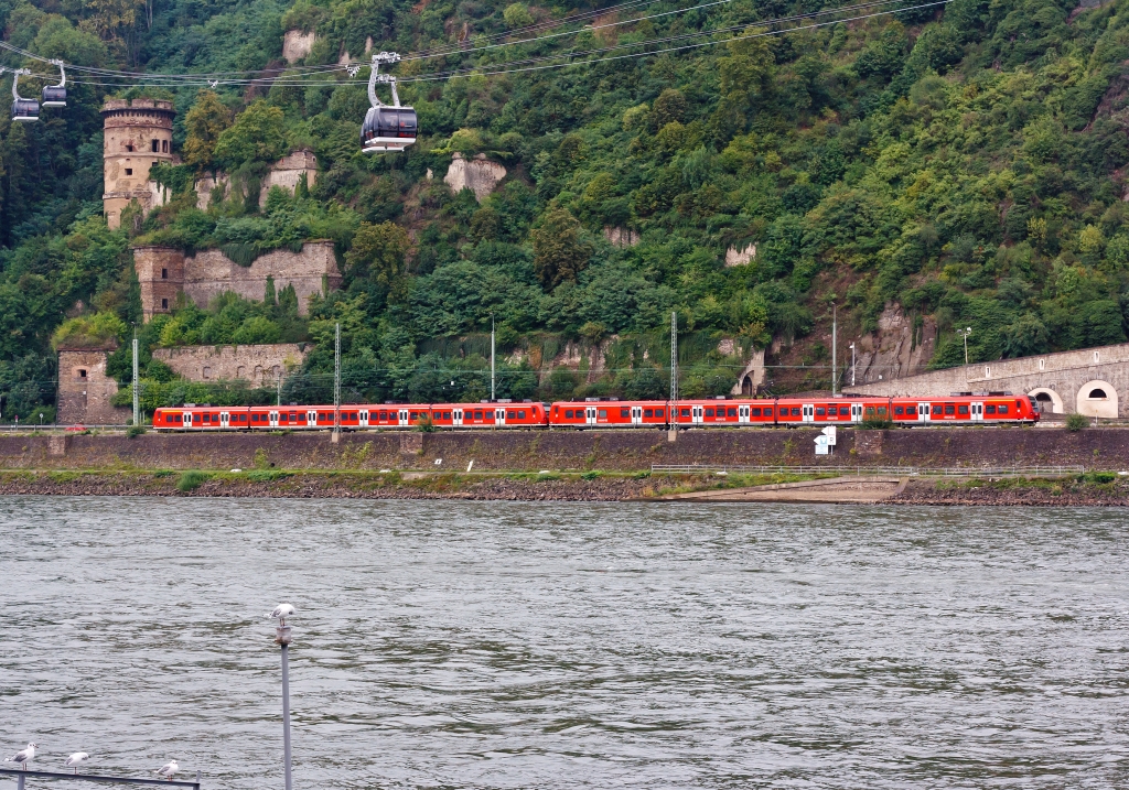 Zwei gekuppelte 425er-Triebz�ge als RE 8 (Rhein-Erft-Express) hat am 13.08.2011 den Bf Koblenz-Ehrenbreitstein verlassen und f�hrt in Richtung K�ln und M�nchengladbach. Dar�ber ist die Rheinseilbahn in Koblenz zusehen.
