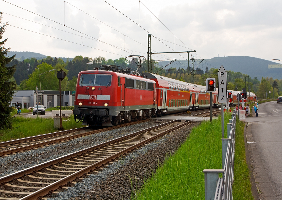 
111 151-7 der DB Regio NRW fährt am 01.05.2014 mit dem RE 9 - Rhein-Sieg-Express (Aachen-Köln-Siegen) in Richtung Siegen, hier beim Bahnübergang in Mudersbach (Bü km 114,7).  

Einen lieben Gruß an den freundlichen Lokführer retour. 

Der Bahnübergang ist eigentlich für LKW über 7,5 t zul. Gesamtgewicht tabu, doch haben immer einige Lkw-Fahrer ihn verbotswidrig überquert, obwohl er zu eng für die langen 40-Tonner ist.  
So hatte sich zuletzt am 26. November 2013, ein Sattelzug sich am Bahnübergang festgefahren und der Regionalexpress RE 9 war in ihn gefahren, zum Glück ohne größere Katastrophe. Drei Personen wurden dabei leicht verletzt, neben dem Zugführer und einem Fahrgast auch ein Passant, der sich in der Nähe aufhielt. 

Nun werden auf der Straße vor und hinter den Bahnübergang eine Konstruktion zur Höhenbegrenzung (2,80 m) aufgestellt, die Fundamente sind schon letzte Woche gemacht worden, und am 19. Mai soll die Montage der eigentlichen Begrenzung erfolgen.

Die 111er wurde 1981 bei Krauss-Maffei AG in München unter der fabriknummer 19863 gebaut. 
Sie hat die NVR-Nummer 91 80 6111 151-7 D-DB und die EBA-Nummer EBA 01G02A 151.