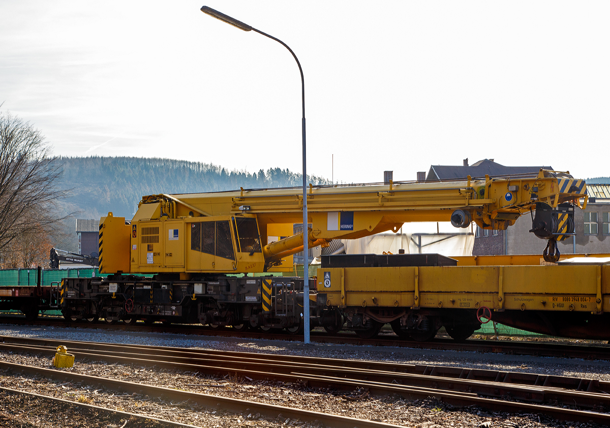 
125t - KIROW Gleisbauschienenkran KRC 810 T „BALU“ der Hering Bau (Burbach), Schweres Nebenfahrzeug Nr. D-HGUI 99 80 9419 023-3, ex 97 82 53 508 19-3, ex 60 80 092 3 931-3, abgestellt am 17.02.2019 in Siegen-Eintracht auf dem Gelände der KSW Kreisbahn Siegen-Wittgenstein GmbH.

Der Kran wurde 1999 von KIROW in Leipzig unter der Fabriknummer 112300 gebaut und an die Hering Bau geliefert. Die Firma Hering Bau gehört in Deutschland zu den größten Eisenbahnkran-Dienstleistern, sie hat 12 eigene Krane.

Der 125-t-Eisenbahndrehkran wird für den Aus-und Einbau von schweren Betonweichen, Gleisjochen und Hilfsbrücken sowie für die Montage von Ingenieurbauwerken eingesetzt. Bei Havarien auf Bahnstrecken leistet er schnelle Hilfe zum Bergen schwerer Lasten.

Technische Daten
Eigengewicht: 128 t
Länge über Puffer: 13.000 mm
Achsanzahl: 8
Drehzapfenabstand: 8.000 mm
Drehzapfenabstand im Drehgestell 1 und 2: 2.300 mm
Achsabstand in den Einzeldrehgestellen: 1.100mm
Ergebene Achsabstände in m: 1,1 / 1,2 / 1,1/ 4,6 / 1,1 / 1,2 / 1,1
Achsfolge: 1'A'1A'A1'A1'
Achslast: 16,0 t
Motorleistung: 235 kW
Fahrgeschwindigkeit im Zugverband: 120 km/h
Fahrgeschwindigkeit mit Eigenantrieb: 20 km/h
zul. Anhängelast: 80 t
Zugelassen als Schwerwagen für Streckenklasse: CS 05
kleinster befahrbarer Radius: 90 m

Tragfähigkeiten:
bei 0,00 m Ausladung vor Puffer, mit Schwerlastausrüstung: 125 t
bei 2,80 m Ausladung vor Puffer, ± 30°, abgestützt: 90 t
bei 2,80 m Ausladung vor Puffer, ± 20°, freistehend: 46 t
