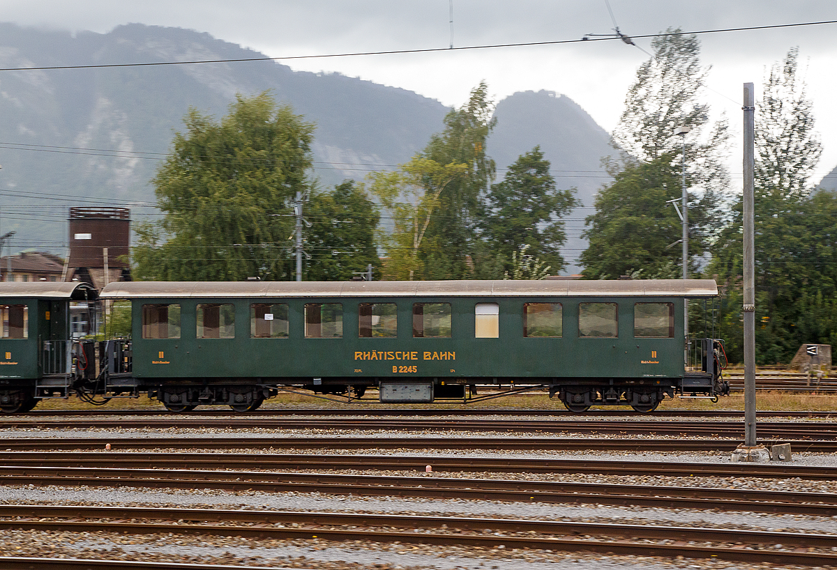 4-achsiger Nostalgie-Plattformwagen RhB B 2245, ex RhB C 2245, ex ChA 51, abgestellt am 12.09.2017 beim Bahnhof Landquart. Aufgenommen aus einem Zug heraus.

Die drei Drehgestell-Plattformwagen B 2245-2247 sind heute Bestandteil vieler RhB-Nostalgiez�ge, ob hinter Dampfloks oder einer der Stangenelloks. Die ab 1956 als B 2245-2249 bezeichneten Vierachser wurden 1928 f�r die Arosalinie von der damaligen Chur-Arosa-Bahn AG (ChA) beschafft. und waren daher bis zur Aufarbeitung 1990 zum Nostalgiewagen mit einer Dachrutenkupplung best�ckt. 

TECHNISCHE DATEN:
Baujahre: 1928
Hersteller:  SIG
Spurweite: 1.000 mm
Anzahl der Achsen: 4
L�nge �ber Puffer: 16.550 mm
Sitzpl�tze: 72 (2.Klasse)
Eigengewicht: 17,0 t
zul�ssige Geschwindigkeit: 70 km/h
Lauff�hig: StN (Stammnetz) / MGB (Matterhorn Gotthard Bahn)
