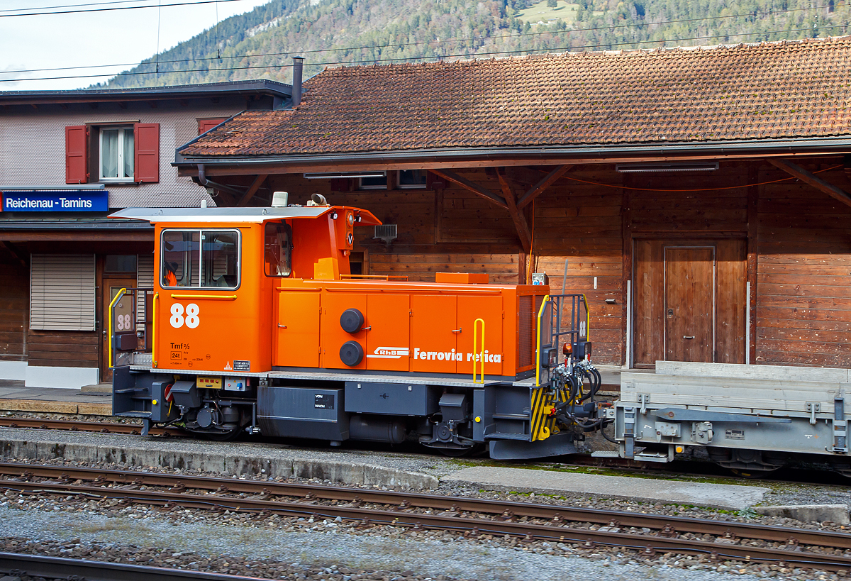 Äußerlich sieht er noch so aus wie der Alte, aber innerlich ist er komplett neu....
Der der aus dem Refitrprogramm gekommene RhB Tmf 2/2 88 ist am 01.11.2019 im Bahnhof Reichenau-Tamins abgestellt, aufgenommen aus einem RhB Zug heraus.

Die Tmf 2/2  wurde 1992 von RACO (Robert Aebi AG, Regensdorf, Schweiz) unter der Fabriknummer 1989 gebaut und an die RhB geliefert. Die RACO Typenbezeichnung ist 420 CT 4H.Die Tmf 2/2 sind die mit Funkfernsteuerung ausgerüsteten Traktoren mit Verbrennungsmotoren der Rhätischen Bahn (RhB). Zwischen 1991 und 1994 wurden von RACO sechs dieser Tmf 2/2 mit den Nummern 85 bis 90 beschafft. Der Tmf 2/2 88 wurde nach dem Umbau in der RhB Werkstatt in Landquart Anfang Oktober 2018 erfolgreich durch das BAV abgenommen und durfte einige Tage später den Betrieb aufnehmen.

Die RhB Tmf 2/2 88 ist der Prototypenumbau, die im Rahmen des Projekts «Refit Baudienstfahrzeuge Tm(f) 2/2» werden die sechs Rangiertraktoren Tmf 2/2 85-90 mit den Baujahren1990 bis 1994, nach und nach, durch diverse Umbau- und Erneuerungsarbeiten fit für die Zukunft gemacht. Zu immer höheren Unterhalts- und Revisionskosten führen nach den Jahren im Betrieb einige Komponenten aus dem Antriebsstrang und dabei vor allem der Cummins-Dieselmotor. Aufgrund seines Alters kann dieser Motorentyp nicht mehr als Neuteil beschafft, sondern nur noch revidiert werden.

Aus diesem Grund hat sich die RhB vor einigen Jahren entschieden, diesen Dieselmotor bei den Tmf 2/2 85-90 zu ersetzen. Nach umfangreichen Untersuchungen wurde bald klar, dass nebst dem Dieselmotor auch einige andere zentrale Fahrzeugkomponenten von Obsoleszenz betroffen sind und weitestgehend nicht mehr den heutigen technischen Ansprüchen genügen. Dazu gehören Getriebe, Partikelfilteranlage, Kühlungsanlage, Hydraulik, Pneumatik, Bremsmechanik wie aber auch die komplette elektrische Einrichtung, die Fahrzeugsteuerung, die Sicherheitseinrichtung und die Fahrdatenvisualisierung. Grob umschrieben in etwa alles außer dem Chassis, Kabine und Achsen.

Antriebsstrang:
Aufgrund der betrieblichen Anforderungen entschied die RhB, den Reihen 6-Zylinder durch einen V8-Dieselmotor von Deutz zu ersetzen. Der neue Motor ist dank seiner V-Bauweise sehr kompakt und kann je nach Drehzahl bis zu 30 % mehr Leistung abgeben als der bestehende. Um diese Leistung optimal auf die Schienen zu bringen, wurde das bestehende Lastschaltgetriebe durch ein automatisches Wendegetriebe der Firma Voith ersetzt. Dieses Getriebe sowie auch die komplette Kühlanlage wurden von Voith auf die Leistungsdaten des Motors optimal abgestimmt. Ein großer Benefit nebst der Leistungssteigerung und der „Einfachheit“  des Antriebsstranges liegt darin, dass die Gangschaltung – mit welcher die restlichen Tmf  2/2 gestraft sind – nicht mehr von Relevanz ist. Dank dem neuen Automatikgetriebe lässt sich die Geschwindigkeit stufenlos und ohne Leistungseinbruch zwischen V null und V max einstellen.

Fahrzeugsteuerung und Fahrdatenvisualisierung
Die bestehende KraussMaffei-Fahrzeugsteuerung wurde durch eine von Selectron, die RhB-Standard ist, ersetzt. Die Antriebsstrangkomponenten (Dieselmotor / Getriebe) wie auch Fahrzeugkomponenten wie beispielsweise Display, Funkfernsteuerung usw. kommunizieren über einen Fahrzeugbus mit der Fahrzeugsteuerung. Dadurch erleichtert sich die Fehlerdiagnose und es konnten viele elektromechanische Komponenten eingespart werden. Die Fahrzeugdaten werden dem Lokführer über Displays visualisiert.

TECHNISCHE DATEN der RhB Tmf 2/2 88 (Refit):
Baujahre: 1991/92 und 1994
Spurweite: 1.000 mm (Meterspur)
Achsfolge: B
Länge über Puffer:  7.490 mm
Achsabstand: 3.750 mm
Breite: 2 700 mm
Eigengewicht:  24 t
Höchstgeschwindigkeit: 60 km/h (60 km/h Schleppfahrt)
Treibraddurchmesser: 	750 mm
Motorentyp: Deutz V8-Dieselmotor 
Weitere Daten wie auch Motor- und Getriebetyp sind mir leider noch unbekannt.
