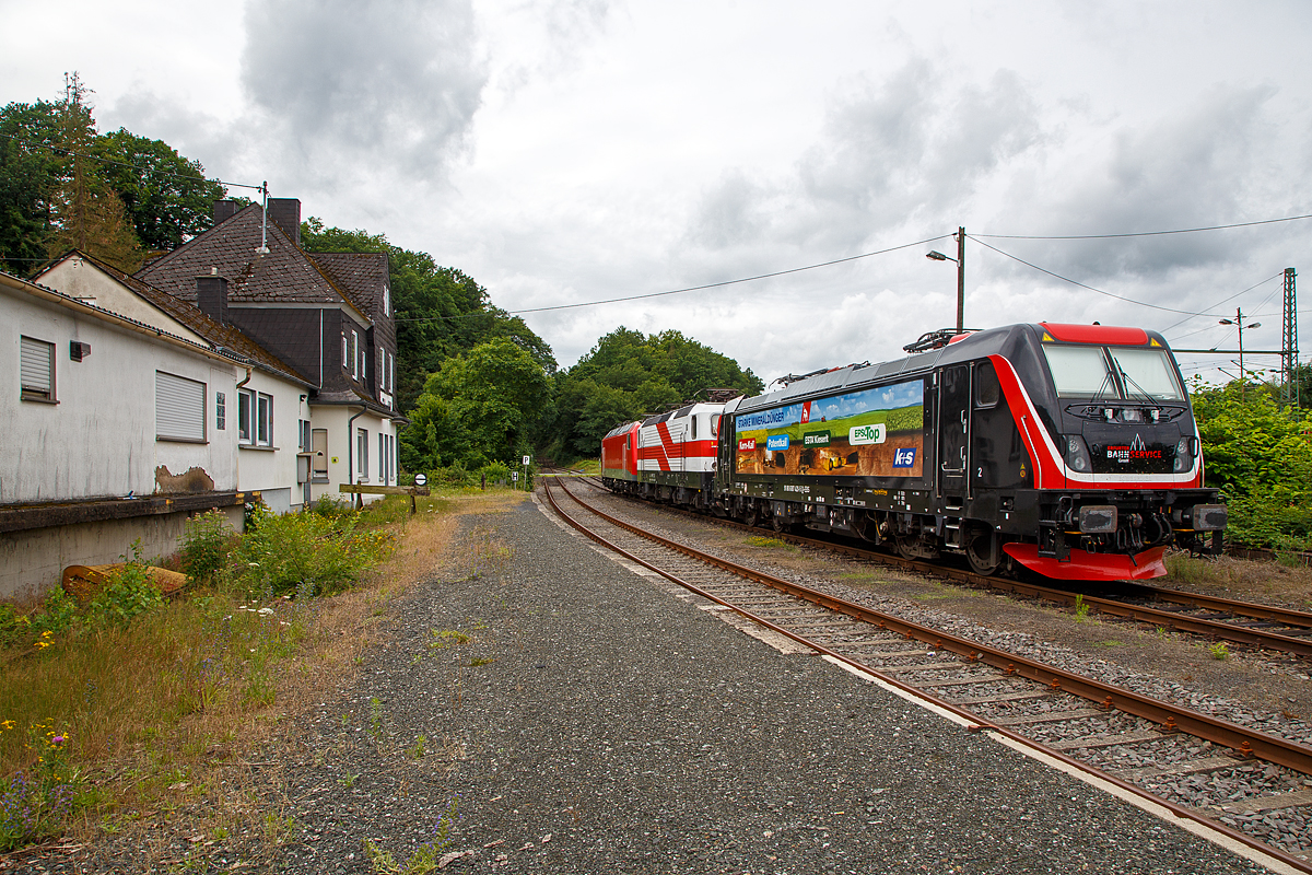 Am 05.07.2021 in Scheuerfeld (Sieg) beim Kleinbahnhof der WEBA (Westerwaldbahn) stehen bereit f�r ihre n�chste Aufgabe, der Abfuhr von schweren Holzz�gen: 
Vorne die Bombardier TRAXX F160 AC3 LM, 187 420-5 (91 80 6187 420-5 D-EBS) der EBS _ Erfurter Bahnservice GmbH.
In der Mitte die  “Wei�e Lady” 143 822-5, alias 243 822-491 80 6143 822-5 D-EBS der EBS - Erfurter Bahnservice GmbH, ex RBH 139, ex DB 143 822-5. ex DR 243 822-4.
Und hinten die 156 002-8 (91 80 6156 002-8 D-FWK) der FWK - Fahrzeugwerk Karsdorf GmbH & Co. KG, ex MEG 802, ex DB 156 002-8, ex DR 252 002-1. 

Hier beim Kleinbahnhof der WEBA (Westerwaldbahn) in Scheuerfeld wird das Fichtenholz von den Holztransport-LKW´s  auf die Schiene verladen. Der komplette Fichtenbestand ist durch den Borkenk�fer in der Region befallen und wird daher abgeholzt. Wer die Region kennt der ist erschreckt wie kahl teilweise die H�nge sind. Ein Gl�ck das es hier nicht nur Fichten, sondern auch Laubwald gibt.