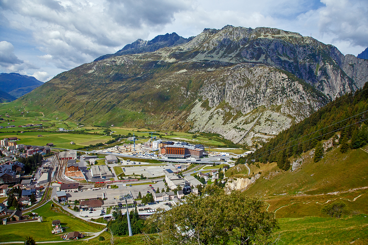 Auf dem Weg von Chur nach Brig...
Nun (am 07.09.2021) fahren wir mit einem MGB Regionalzug von Disentis/Must�r �ber den Oberalppass nach Andermatt und blicken nun auf den Bahnhof Andermatt.
Nach rechts geht das Gleis der Sch�llenenbahn nach G�schenen. Auf dem Nebengleis ist eine Deh 4/4 mit einem Zug abgestellt. Links unten ist das Gleis woraus wir gleich einfahren.

Auch links unten im Bild (rechts vom Gleis) die Talstation der im Dezember 2017 er�ffneten 8er Gondelbahn (Ein-Seil-Umlaufbahn)   G�tsch-Express   (Andermatt – N�tschen - G�tsch). Sie f�hrt ab Bahnhof Andermatt �ber die neue Mittelstation am N�tschen zur Bergstation G�tsch. Die neue Anlage hat eine F�rderleistung von 2.400 Personen pro Stunde, die Geschwindigkeit betr�gt 5 Meter pro Sekunden und die Fahrzeit betr�gt ca. 8 Minuten.
