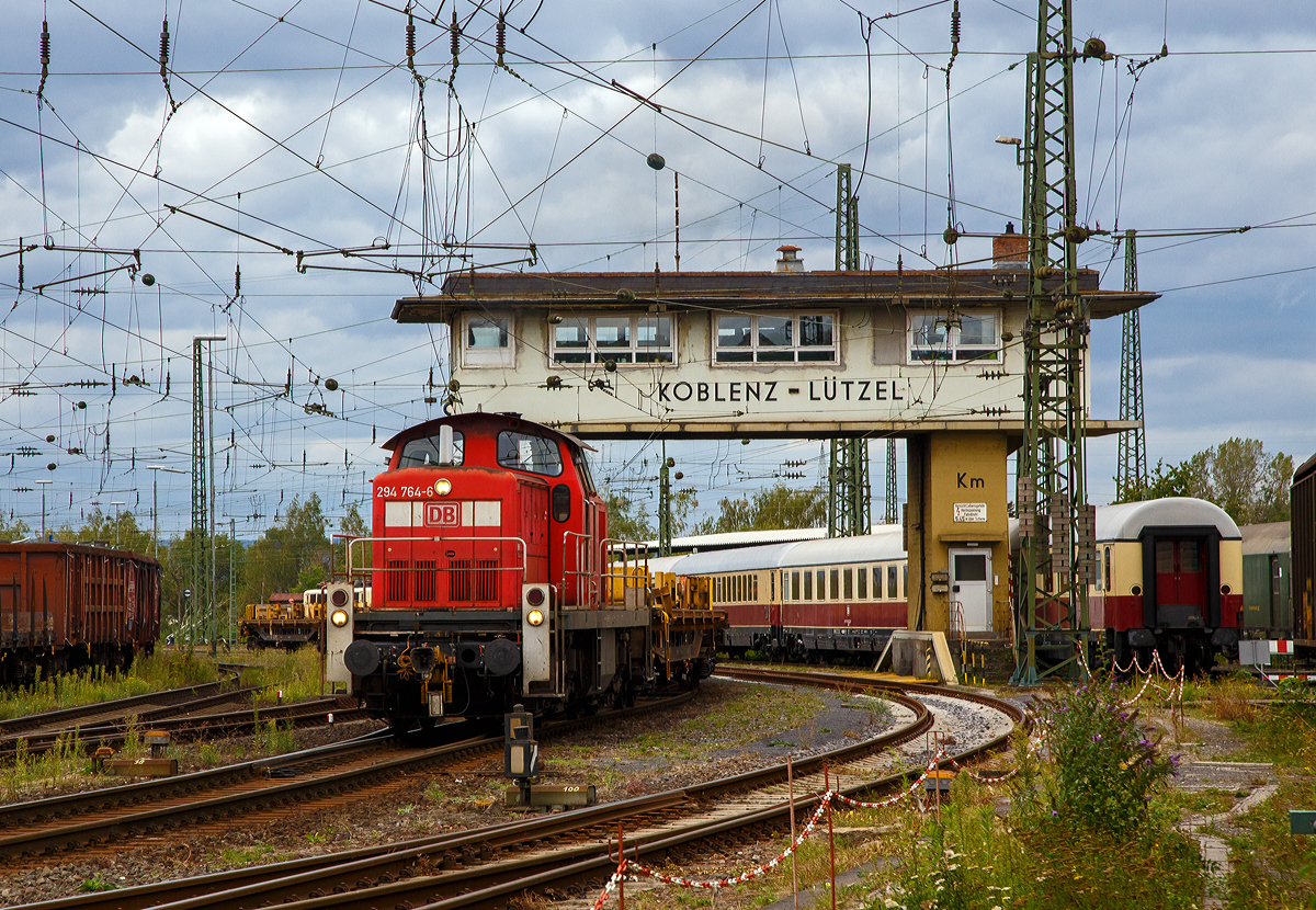 Bei bzw. unter den Reiterstellwerk Koblenz-Lützel Km rangiert am 04.09.2020 die 294 764-6 (98 80 3294 764-6 D-DB), ex DB 290 764-0, ex DB 290 264-1, eine remotorisierte V 90 der DB Cargo AG, mit einem leeren Schienenzug. Das elektromechanische Weichenwärter-Stellwerk, der Bauform Siemens & Halske S&H 1912 (alte Farbscheibenanordnung) ist noch in Betrieb. (Aufnahme aus dem DB Museum heraus).

Die Lok wurde 1972 bei MaK in Kiel unter der Fabriknummer 1000562 gebaut und als 290 262-2 an die DB geliefert. Anders als so viele V 90 fuhr sie recht lange ohne Funkfernsteuerung und wurde erst zur 290 764-0 remotorisiert, bevor sie eine 294er wurde.

 Im Jahr 2002 erfolgte durch die DB Fahrzeuginstandhaltung GmbH, in Cottbus eine Remotorisierung durch einen neuen MTU 90° V-8-Zylinder-Dieselmotor mit Common-Rail-Einspritzsystem, Abgas-Turbolader und Ladeluftkühlung, vom Typ 8V 4000 R41. Der Motor ist auf eine Leistung von 1.000 kW (1.341 PS) bei 1.800 U/min gedrosselt. Auch wurden eine neue Lüfteranlage und ein neuer Luftpresser eingebaut, zudem bekam die Lok ein Umlaufgeländer. Durch die Remotorisierung und den Umbau erfolgte auch die Umzeichnung in 290 764-0. 

Erst 2004 erfolgte dann die Ausrüstung mit Funkfernsteuerung (Typ Krauss-Maffei) und Umzeichnung in die heutige 294 764-6.
