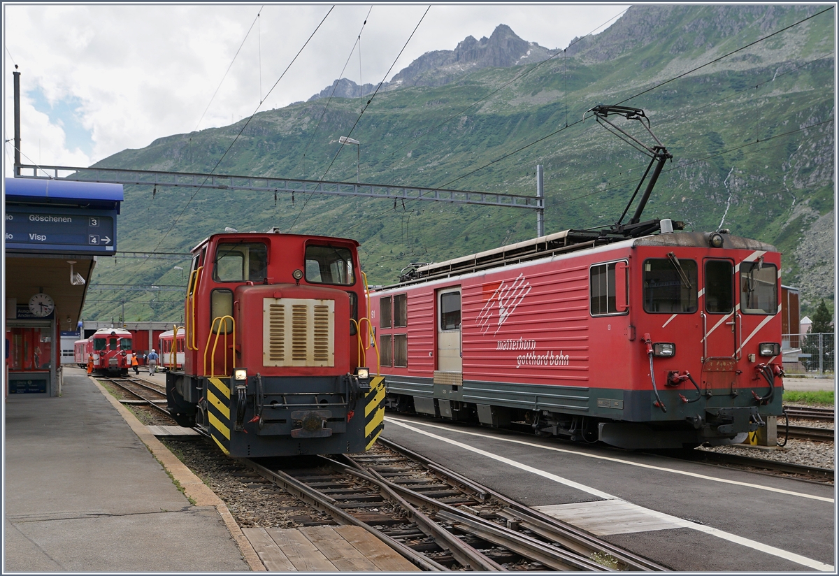 Da auf der steilen Schöllenen Bahn die Anhängelast begrenzt ist, werden jeweils in Andermatt die von Visp kommenden Verstärkungswagen abgehängt und dann gleich dem Gegenzug übergeben. 
Hier holt die  Schöma  Disellok nach der Ausfahrt des Zuges nach Göschenen die Wagen ab, während rechts der BDeh 4/4 54 (mit seinem Regionalzug nach Visp) für das Ankuppeln der Verstärkungswagen bereit steht.
28. Juli 2016