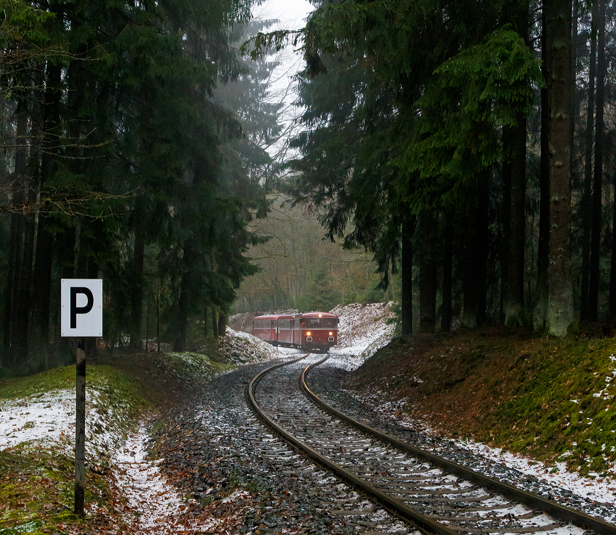 
Da kommen sie hinab vom Pfannenberg....
Eine Schienenbusgarnitur der VEB Vulkan-Eifel-Bahn Betriebsgesellschaft mbH auf Sonderfahrt (bestehend aus 798 670-6, 998 863-5 und 796 784-7) fährt am 26.01.2019 von der ehem. Grube Pfannenberger Einigkeit  (heute Sitz der Schäfer Werke) hinab zur Spitzkehre Pfannenberg bei Neunkirchen-Salchendorf. 

Die Garnitur befährt die priv. Strecke der Kreisbahn Siegen-Wittgenstein (Betriebsstätte Freien Grunder Eisenbahn - NE 447). Heute gibt es zwischen Herdorf und der Grube Pfannenberger Einigkeit noch jeden Werktag Güterverkehr, obwohl die Erzgrube Pfannenberger Einigkeit ihren Betrieb im April 1962 aufgegeben hat. An ihrer Stelle benötigen seitdem die Schäfer Werke KG den Anschluss für die Zulieferung von Stahl Coils sowohl als Rohstoff als auch für ihren Handel mit deren Zuschnitten nach Kundenwunsch.
