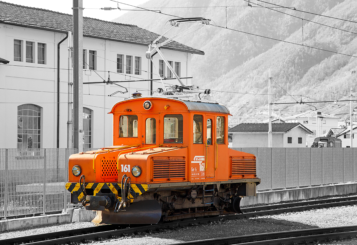 
Das RhB  Eselchen  161 bzw. der Rangiertraktor RhB Ge 2/2 161, ex BB Ge 2/2 61 steht am 18.02.2017 im RHB-Bahnhof Tirano. 

Der RHB-Bahnhof Tirano ist der Endbahnhof der Berninabahn und bedingt dadurch ein Kopfbahnhof. Bei den meist von Triebwagen geführten Züge werden dann die Personenwagen (teilweise auch Güterwagen) abgehangen und von der RhB Ge 2/2 auf ein anderes Gleis rangiert. Danach setzt der Triebwagen um und setzt sich für die Gegenrichtung wieder vor die Wagen.

Von der kleinen Elektrolokomotive Ge 2/2 wurden nur zwei Loks von diesem Typ für Berninabahn (BB) , heute der Rhätischen Bahn (RhB), gebaut, ursprünglich die BB 61 und BB 62, seit 1961 mit den Nummern RhB 161 und 162.

Beide Gleichstromloks wurden 1911 von der Berninabahn (BB) für Vorspanndienste beschafft, sie wurden von SIG und Alioth gebaut. Die damals noch braun lackierten Maschinen erhielten die Nummern Ge 2/2 61 und 62 und waren noch mit Lyra-Stromabnehmern bestückt. Nach der Übernahme der BB durch die RhB im Jahre 1942 wurden sie verschiedentlich modernisiert; sie tragen heute einen Einholmstromabnehmer und sind meistens als Rangierloks in Tirano und Poschiavo tätig.

Sie werden wegen ihrer Form auch  Mini-Krokodile  oder wegen ihres Aufgabenbereichs  Eselchen  genannt.  Zwischen den Vorbauten ist ein Gang, so dass ein Übergang zum Zug möglich war. Die Benutzung ungeschützter Übergänge ist aber inzwischen selbst dem Personal untersagt, so wurden folgerichtig an den beiden Loks die Übergangsbleche entfernt. Die Loks sind die zweitältesten im Dienst befindlichen Lok der RHB.

Technische Daten der Ge 2/2
Betriebsnummern: 161 und 162 (ex 61 und 62)
Hersteller: SIG, Alioth
Baujahr: 1911
Anzahl Fahrzeuge: 2
Spurweite: 1.000 mm
Achsanordnung: B
Länge über Puffer: 7.740 mm
Breite: 2.500 mm
Achsabstand: 
Triebraddurchmesser (neu): 975 mm
Dienstgewicht:  18.0 t
Höchstgeschwindigkeit: 45 km/h
Stundenleistung: 250 kW (340 PS)
Anfahrzugkraft: 37,6 kN
Stundenzugkraft: 27,5 kN bei 27 km/h
Motorentyp:  Gleichstrom Reihenschluss
Fahrleitungsspannung: 1 kV DC (Gleichstrom) / 750 V DC vor 1935 
