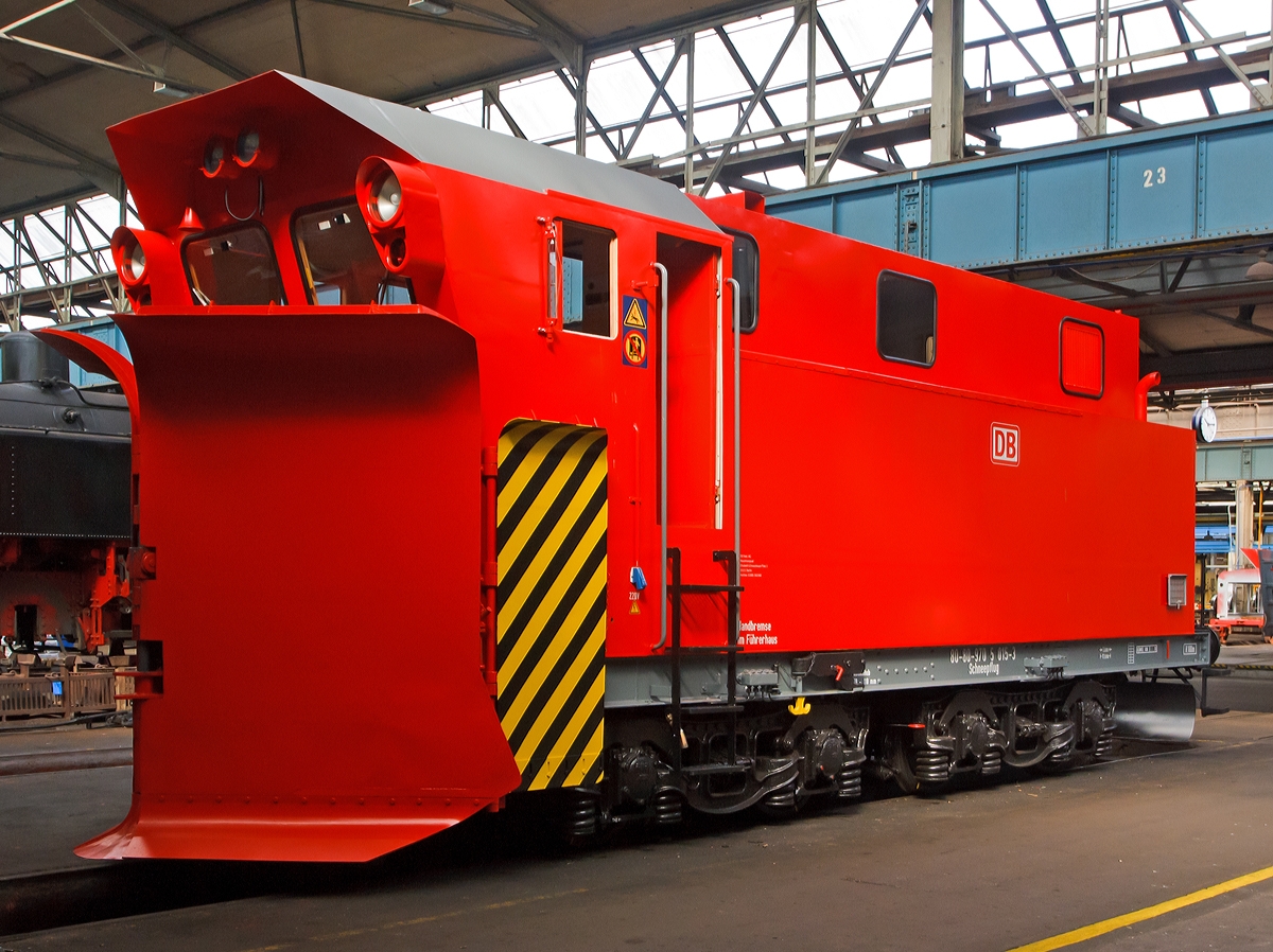 Der m�chtige Schneepflug 80-80-970 5 015-3 (ex 80 50 979 4 212-4) der Bauart Meiningen W (Baureihe 855, bzw. Schneepflug BA 855) steht am 24.08.2013 im Dampflokwerk Meiningen.

Die Schneepfl�ge der Bauart Meiningen wurden von 1968 bis 1981 gebaut. Die ersten vier Pfl�ge wurden im Reichsbahnausbesserungswerk (RAW) Halberstadt, alle weiteren im RAW Meiningen, das heute Dampflokwerk Meiningen hei�t. Die erste Serie umfasste 50 Fahrzeuge, die sp�ter zur Unterscheidung die Bezeichnung „Schneepflug Meiningen“ erhielten. Die zweite, ab 1978 gebaute, verbesserte Serie von 55 Fahrzeugen erhielt die Bezeichnung „Schneepflug Meiningen W“ (W f�r Wechselsprechanlage).
Alle 105 Schneepfl�ge wurden 1994 in die Deutsche Bahn AG eingebracht. Die Pfl�ge erhielten von der Deutschen Bahn die Baureihennummer 855.
Um den Einsatzradius zu vergr��ern und den Bestand zu reduzieren baute die DB AG 30 Fahrzeuge um. Dabei wurde u.a. die H�chstgeschwindigkeit von 50 km/h auf 100 km/h erh�ht. 1999 waren davon nur noch 30 Fahrzeuge im Bestand. Zahlreiche dieser Schneepfl�ge wurden an Privatbahnen verkauft.
Der Meiningen-Pflug ist ein Ein-Richtungs-Schneepflug, ist also nicht auf dem Fahrgestell drehbar. Er verf�gt �ber keinen eigenen Antrieb, sondern ist auf eine Schiebelokomotive angewiesen. Als Fahrgestell dienen Rahmen und Drehgestelle ausgemusterter Schlepptender des Typs 2'2'T32. Durch einen Betonballast wird das Gewicht des Schneepflugs auf 54 Tonnen gebracht.
Die Pflugschare sind nach dem von Rudolf Klima entwickelten Prinzip konstruiert, somit ist es auch ein Klima-Schneepflug, (senkrecht stehende Schare, in Grundstellung keilf�rmig zur zweiseitigen R�umung, ausschwenkbar zur einseitigen R�umung), mit Seitenr�umfl�geln. Zus�tzlich ist ein keilf�rmiger Spurinnenr�umer vorhanden.

Technische Daten:
L�nge �ber Alles: 11.500 mm
Eigengewicht: 54 t
Zur Mitfahrt zugel. Personen: 6
H�chstgeschwindigkeit: 100 km/h

