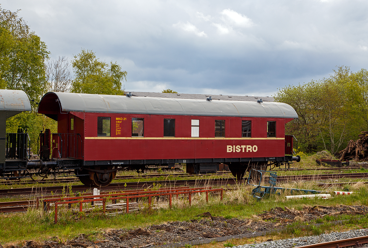 Der MKO 21 – Buffetwagen (heutige UIC-Nr. 75 80 2429 331-1 D-MKO), eine zweiachsige Donnerb�chsen, der MKO - Museumseisenbahn K�stenbahn Ostfriesland e. V. am 01.05.2022 auf dem Museumsareal in Norden, gleich neben dem Bahnhof Norden.

Ende der 1920er Jahre beschaffte die Deutsche Reichsbahn Gesellschaft (DRG) eine Serie neuer zweiachsiger Sitzwagen mit offenen Endb�hnen und �berg�ngen. Sie entstanden in genieteter Ganzstahlbauweise. Die Wagen entwickelten bauartbedingt ein wohl etwas dr�hnendes Fahrger�usch, das ihnen den Spitznamen „Donnerb�chsen“ einbrachte. Nach dem Ausscheiden der Wagen aus dem Personenzugdienst wurden viele zu Bauzugwagen umgebaut und fristeten danach vielerorts als Bahnhofswagen ihr Dasein.

Bei diesem Wagen handelt es sich urspr�nglich um ein 3. Klasse- Fahrzeug. Der Wagen wurde in mehrj�hriger Arbeit von den Vereinsmitgliedern aufgearbeitet. Nach vorsichtiger Entfernung etlicher Farbschichten konnten die Originalanschriften wieder freigelegt und somit die Wagennummer ermittelt werden. Der Innenraum erhielt je zur H�lfte Holzb�nke nach altem Muster und eine Buffetausstattung. 1993 wurde der Wagen in den Einsatzbestand eingereiht.

TECHNISCHE DATEN:
Hersteller: MAN 
Baujahr: 1928
Spurweite: 1.435 mm (Normalspur)
Bauart: Ci-28 (CiBuf)
Wagennummer: DRG Ci 84 024, DB 60 355
Anzahl der Achsen: 2
L�nge �ber Puffer: 13.920 mm
Wagengewicht: 20.600 kg
Sitzpl�tze: 28
