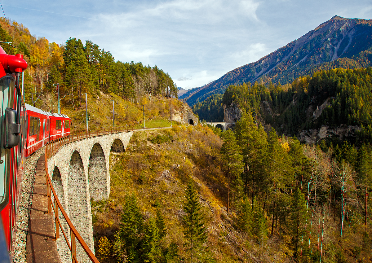 Der RhB ABe 8/12 - 3511  Otto Barblan  (ALLEGRA-Zweispannungstriebzug) mit dem RhB Alvra-Gliederzug als IR von Chur nach St. Moritz, f�hrt am 01.11.2019 �ber das Schmittentobel-Viadukt (35 m hoch, 137 m lang), danach folgt der 27 m lange Zalaint-Tunnel und das Lehnenviadukt (nicht im Bild), bevor es dann �ber das ber�hmte Landwasserviadukt und gleich anschlie�enden durch den 216 m langen Landwasser-Tunnel geht. 