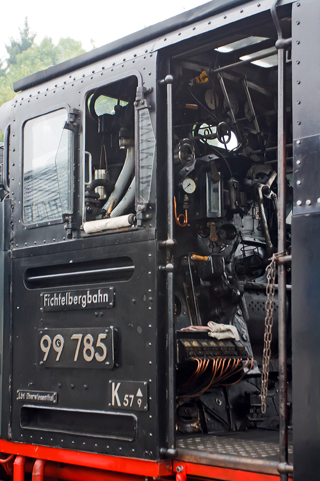 
Detail bzw. Blick in den F�hrerstand von der 99 785 der Fichtelbergbahn (ex DB 099 749-4, ex DR 99 1785-7) am 25.08.2013  in Oberwiesenthal. 

Diese Lok der Baureihe 99.77-79 (s�chsische VII K Neubau) wurde 1953 bei VEB Lokomotivbau Karl Marx, Babelsberg (vormals O&K) unter der Fabriknummer 32026 gebaut, 1992 erfolgte eine Rekonstruktion im Raw Meiningen (mit Kessel-Nr. 1476 und Rahmen-Nr. 12).  Neben der Baureihe 99.73-76 (s�chsische VII K Altbau) geh�ren diese Lokomotiven mit 600 PS (441 KW)Leistung zu den Leistungsst�rksten Loks der Spurweite 750 mm.