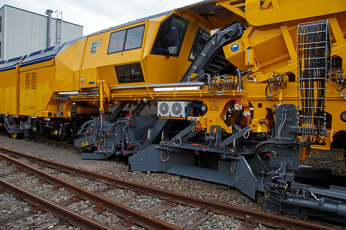 Detailbild Schotterpflug der Plasser & Theurer UNIMAT 09-8x4/4S BR Dynamic E³, präsentiert auf der iaf 2022 in Münster (hier am 31.05.2022), eingestellt als A-PLA 99 81 9121 003-3 der Franz Plasser Vermietung von Bahnbaumaschinen. Die fast 69 m lange Maschine ist eine innovative Kombination aus Weichen- und Streckenstopfmaschine mit Planierkapazität und dynamischem Gleisstabilisator.