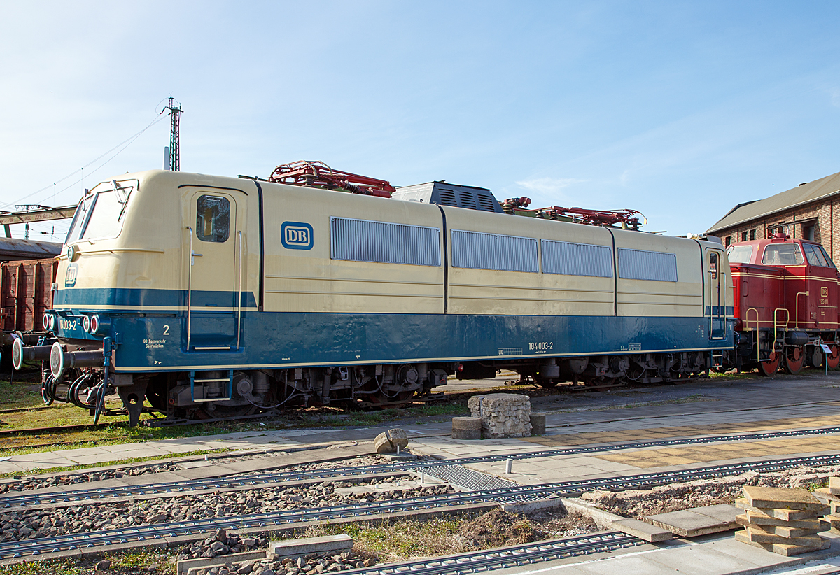 Die 184 003-2, ex DB E 410 003, am 25.03.2017 ausgestellt im DB Museum Koblenz-Lützel.

Die Mehrsystem-Elektrolokomotive wurde 1966 bei Krupp in Essen unter der Fabriknummer 4837 gebaut, der elektrische Teil ist von AEG. Bei der Deutschen Bundesbahn (DB) wurde sie als E 410 003 in Dienst gestellt. Mit der Einführung der EDV-Nummer wurde sie zum 01.01.1968 umgezeichnet in DB 184 003-2. Am 01.04.2002 wurde sie bei der DB AG ausgemustert.

Um einen zeit- und arbeitsintensiven Lokwechsel in den Grenzbahnhöfen zu vermeiden, vergab die Deutsche Bundesbahn 1964 einen Entwicklungsauftrag an AEG, BBC sowie Krupp. Aufgabe war die Entwicklung einer Lokomotive, die den Fahrstrom aus unterschiedlichen Netzsystemen beziehen konnte. Da in den 1960er Jahren der grenzüberschreitende Verkehr nach Frankreich, Belgien und Luxenburg zunahm, entschied man sich bei der Entwicklung für eine vier Systemlokomotive.

Die Baureihe E 410 verfügte über die Ausrüstung zum Betrieb unter mehreren verschiedenen Oberleitungsspannungen. Sie konnte Einsätze unter dem deutschen (15 kV 16,7 Hz) und dem französischen (25 kV 50 Hz) Wechselstromsystem sowie dem belgischen und französischen Gleichstromnetz (3 kV bzw. 1,5 kV) fahren und brachten ihr schnell den Beinamen „Europa-Lok“ ein. Als charakteristisches Merkmal hatte die Baureihe E 410 ursprünglich vier Stromabnehmer.
Die ersten fahrplanmäßigen Einsätze erfolgten vor Schnellzügen zwischen Köln und dem belgischen Lüttich ab Sommer 1969. Beheimatet waren die 184 im Bw Köln-Deutzerfeld . Die Thyristor-Stromrichter, mit denen die Phasenanschnittssteuerung realisiert wurde, bereiteten im Netz der belgischen Staatseisenbahnen trotzdem Probleme. Außerdem kam es zu häufigen Lokausfällen aufgrund plötzlich auftretender starker Spannungsschwankungen im belgischen Gleichstromnetz. Der Einsatz im belgischen Netz wurde daher zum 26. September 1971 beendet. Daraufhin kamen die Loks aber im Nahverkehr rund um Köln zum Einsatz, teilweise mit D-Zügen sogar bis nach Rheine. Weil die Lokomotiven so aber nicht wirtschaftlich eingesetzt waren, zog die Bundesbahn 1979 die Maschinen nach Saarbrücken ab und legte die Systeme für Gleichstrombetrieb, einschließlich der betreffenden Stromabnehmer, still.

Aus dieser Baureihe wurden später auch die vier Zweisystemlokomotiven der Baureihe E 310 (ab 1968: Baureihe 181.0) abgeleitet.

Aus der Achsfolge Bo'Bo' geht hervor, dass die Lokomotiven zwei Drehgestelle mit insgesamt vier Fahrmotoren und damit vier angetriebenen Achsen besitzt. Die Kraftübertragung erfolgt mittels Gummiring-Kardanantrieb. Erstmals wurden Drehgestelle mit Lemniskatenanlenkung für besseren Kurvenlauf angewendet. Da die Baureihe 184 sowohl mit Wechsel- als auch mit Gleichstrom betrieben werden sollte, wurden Mischstrommotoren benötigt. Die Lösung fand man in fremdbelüfteten sechspoligen Motoren für Spannungen bis 1500 V.

Nicht nur hier wurde damals hochmoderne Technik verwendet, aus den Mischstrommotoren ergaben sich auch besondere Anforderungen an die Steuer- und Stromrichterelektronik: so mussten Thyristoren eingebaut werden, die eine stufenlose Phasenanschnittsteuerung ermöglichten. Mechanische Schaltwerke entfielen somit und zusammen mit dem guten Kraftschluss zwischen Schiene und Rad wurde eine ebenso gute Regelbarkeit von Geschwindigkeit und Zugkraft erreicht.

Um einen Betrieb mit der geringeren Fahrdrahthöhe in Frankreich zu ermöglichen, wurde die Bauhöhe des Lokkastens dem französischen Umgrenzungsprofil angepasst. Die knapp 17 Meter langen, 84 Tonnen schweren Lokomotiven erreichen bei Dauerleistungen von 3000 Kilowatt Geschwindigkeiten von bis zu 150 km/h.

TECHNISCHE DATEN:
Spurweite: 1.435 mm
Achsfolge: Bo'Bo'
Treibrad-Durchmesser: 1.250 mm
Eigengewicht: 84,0 t
Länge über Puffer: 16.950 mm
Höchstgeschwindigkeit: 150 km/h
Antrieb: Gummiring-Kardan
Leistung: 3.000 kW bei 91km/h
Zugkraft: 275 kN
Stromsysteme: 15 kV 16 2/3 Hz / 25 kV 50 Hz (1,5 kV DC / 3 kV DC)
Kupplungsart: Schraubenkupplung 