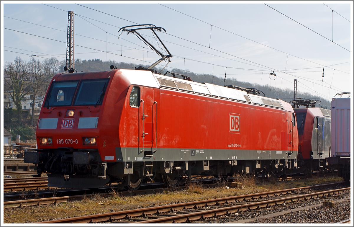 Die 185 070-0 der DB Schenker Rail Deutschland AG steht am 08.03.2014 in Kreuztal im Abstellbereich und macht sich mit der (verdeckten) 145 084-0 zur Fahrt zum Rangierbahnhof bereit, um einen Güterzug zuübernehmen. 

Die TRAXX F140 AC1  (BR 185) wurde 2002 bei Bombardier in Kassel unter der Fabriknummer 33485  gebaut. Sie trägt die NVR-Nummer 91 80 6185 070-0 D-DB und die EBA-Nummer EBA 99A22A 070.
