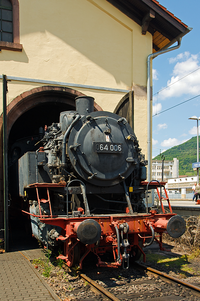 
Die 64 006 (ex DB 064 006-0) schaut aus dem Lokschuppen heraus...
Am30.05.2014 im Eisenbahnmuseum Neustadt an der Weinstraße (Pfalzbahn - Museum). 

Die die Baureihe 64 ist eine Einheits-Personenzugtenderlokomotive der Achsfolge 1'C1' mit niedriger Achslast. Von vorne bis zum Führerhaus hat die BR 64 sehr große Ähnlichkeit mit der BR 24, das kommt aber auch nicht von ungefähr, denn viele Teile des Triebwerkes und der Kessel wurden von der Baureihe 24 übernommen.

Die hier zusehende Lok 64 006 wurde 1928 von der Lokomotivfabrik Borsig in Berlin) unter der Fabriknummer 11962 gebaut und an die DRG geliefert. Nach dem Krieg blieb sie im Westen und kam zu Deutschen Bundesbahn als DB 64 006, in Jahr 1968 erfolgte die Umzeichnung in DB 064 006-0, so war sie bis 1972 im Einsatz und wurde 1973 bei der DB ausgemustert und ging Privateigentum nach Elmstein bis sie 2001 von der DGEG - Deutsche Gesellschaft für Eisenbahngeschichte übernommen wurde.
