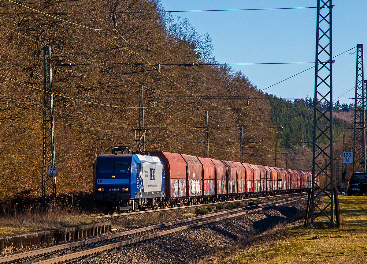 Die an die RBH Logistics vermietete 145 069-1 (91 80 6145 069-1 D-DB) der DB Cargo AG fährt am 01.03.2021, mit einem Schüttgutwagenzug (leere 4-achsige offene Schüttgutwagen mit schlagartiger Schwerkraftentladung der Gattung Falns 121), durch Dillbrecht an der Dillstrecke (KBS 445) in Richtung Siegen.

Die TRAXX F140 AC wurde 2000 von Adtranz in Kassel unter der Fabriknummer 33396 gebaut und an die DB geliefert, bis 2018 fuhr si für die DB Cargo und wurde dann an die RBH Logistics GmbH in Gladbeck vermietet und dort unter der internen Nummer RBH 228 geführt. 

Die RBH Logistics ist ein Tochterunternehmen der DB Cargo Deutschland AG und die Nachfolgegesellschaft von Werks-, Zechen- und Hafenbahnen im Raum der Bergwerksdirektion Recklinghausen. Durch die verschiedenen Firmenzusammenschlüsse und -aufteilungen ergab sich seit 1913 eine wechselvolle Geschichte. Das heute als Teil des Firmennamens genutzte Akronym RBH stand einige Jahre für die RAG-Bahn- und Hafenbetriebe und wurde beim Verkauf von dieser an die Railion Deutschland im Jahr 2005 beibehalten. Nach damaliger Angabe des neuen Eigentümers stehen die Buchstaben R, B und H nun für die Kernkompetenzen des Unternehmens: Eisenbahnverkehr (Rail), Binnenschifffahrt (Barge) und Hafenumschlag (Harbour).