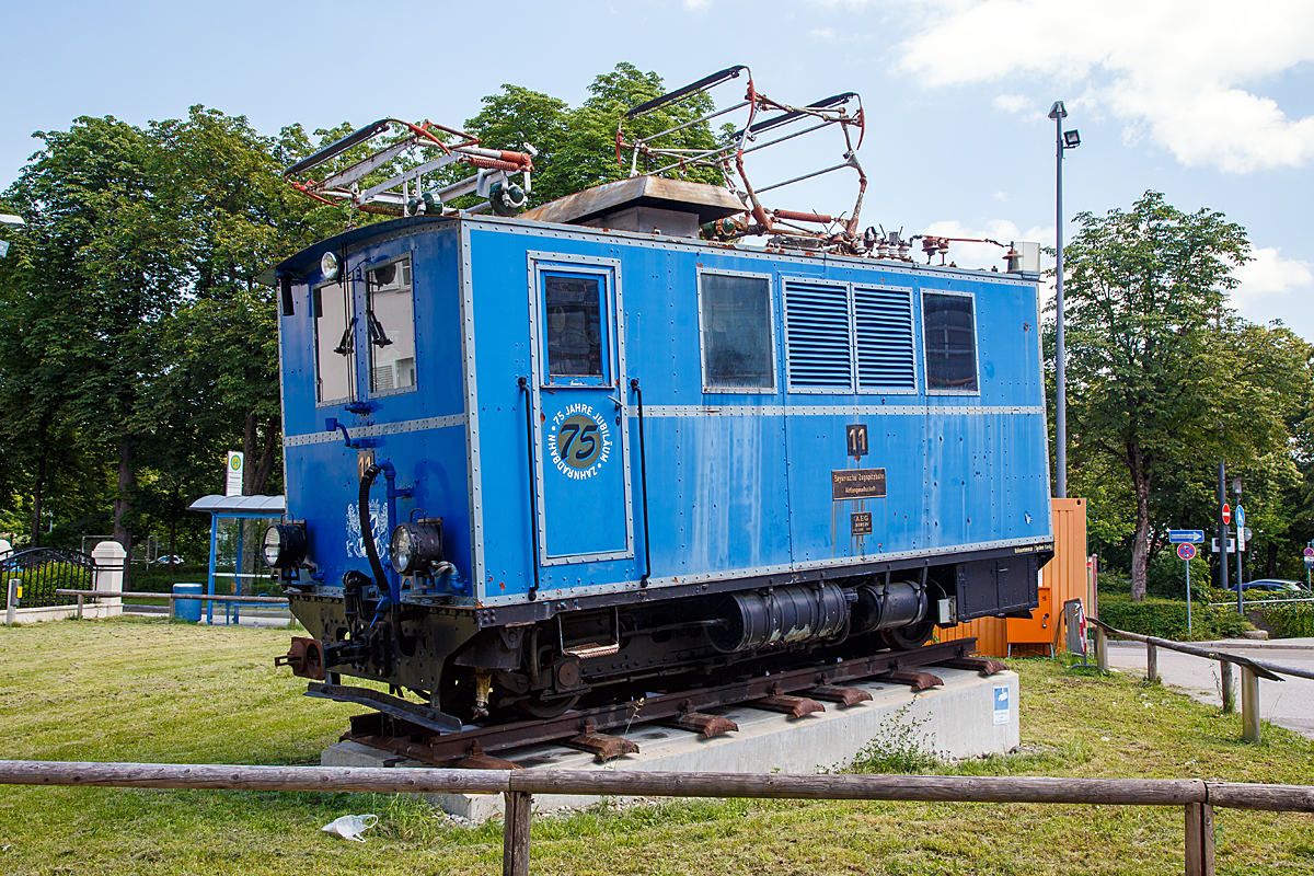 Die Berglokomotiven 11 (Zahnradlokomotive) der Bayerische Zugspitzbahn AG als Denkmal beim Verkehrszentrum des Deutschen Museums in M�nchen am 16.06.2018. 

Die Lok wurde 1929 von AEG in Berlin unter der Fabriknummer 4260 gebaut. Seit April 2008 steht sie zusammen mit der Tallokomotive 3 als Denkmal vor dem Verkehrszentrum des Deutschen Museums in M�nchen, sie sind eine Leihgabe der BZB ans Museum.

Die Bayerische Zugspitzbahn ist neben der Wendelsteinbahn, der Drachenfelsbahn und der Zahnradbahn Stuttgart eine von vier noch betriebenen Zahnradbahnen in Deutschland. Die meterspurige Strecke f�hrt vom Garmisch-Partenkirchner Ortsteil Garmisch auf die Zugspitze (7,5 km �dh�sionsstrecke und 11,5 km Zahnradstrecke) den h�chsten Berg Deutschlands. Sie wird von der Bayerischen Zugspitzbahn Bergbahn AG (BZB) betrieben.

Die zweiachsigen Berglokomotiven k�nnen nur auf Zahnstangenabschnitten eingesetzt werden. Sie sind in der Lage zwischen Grainau und Eibsee drei Wagen mit insgesamt 36 Tonnen und zwischen Eibsee und Zugspitze zwei Wagen mit insgesamt 24 Tonnen zu bef�rdern. Jeder der drei 170 Kilowatt starken Motoren arbeitet unabh�ngig �ber ein eigenes Getriebe auf jeweils ein Triebzahnrad. 

�ber die komplette L�nge des Rahmens erstreckt sich ein geschlossener Kastenaufbau, an dessen talseitigen Ende der F�hrerstand angebracht ist. Die Bef�rderung von Wagen erfolgt immer mit der Lokomotive auf der Talseite. Da sich somit der Lokf�hrer bei einer Bergfahrt nicht an der Spitze des Zuges befindet, f�hrt im Schutzh�uschen des vordersten Wagens ein Zugbegleiter mit, der �ber Klingenzeichnen mit dem Lokf�hrer in Verbindung steht. Im Gefahrenfall kann der Zugbegleiter �ber ein Notbremsventil der Vakuumbremse den Zug zum Halten bringen. Im Falle einer Notbremsung werden die Fahrmotoren automatisch abgeschaltet, um ein Auflaufen der Lokomotive auf den Zug zu verhindern.

Als Betriebsbremse wird eine Widerstandsbremse verwendet, die unabh�ngig von der Fahrdrahtspannung arbeitet. Zus�tzlich besitzen die Lokomotiven noch zwei Handbremsen, die unabh�ngig voneinander auf alle drei Zahnr�der wirken und die Vakuumbremse, die ebenfalls auf alle drei Zahnr�der wirkt. Diese wirken dabei als Reibbremsen auf Bremsscheiben, die auf der Triebzahnradwelle angebracht sind. Sie dienen dazu, den Zug zum Halten zu bringen. Zwei zus�tzliche Geschwindigkeitsbremsen �berwachen jeweils die H�chstgeschwindigkeit von 9 bzw. 13 km/h und l�sen bei deren �berschreitung selbstt�tig eine Notbremsung aus. 

Von Anfang an wurden alle Fahrzeuge mit einer selbstt�tigen Mittelpufferkupplung der Bauart Scharfenberg ausger�stet. 
Des Weiteren wurde die erste Generation von Fahrzeugen (wie dieses) mit selbstt�tigen Vakuumbremsen der Bauart Hardy ausgestattet. 
Die Berglokomotiven 11 bis 18 und die Triebwagen 1 bis 6 sind mit Eiskratzern ausgestattet, welche die Oberleitung von Schnee und Eis reinigen. Mit den Eiskratzern werden Kontaktprobleme des Stromabnehmers bei Eis an der Oberleitung und damit die Bildung von Lichtb�gen unterdr�ckt.

Wie bei elektrischen Zahnradbahnen �blich erfolgt auch bei der Zugspitzbahn die Betriebsbremsung bei Talfahrten mit elektrischen Bremsen, da diese in der Lage sind die Geschwindigkeit verschlei�frei konstant zu halten. Aber mit Widerstandsbremsen und nicht mit elektrischen Nutzbremse. Die Widerstandsbremse wirkt dabei netzunabh�ngig, d. h. die Bremse funktioniert auch noch bei Ausfall der Fahrleitungsspannung.

TECHNISCHE DATEN:
Spurweite:	1.000 mm (Meterspur)
Achsfolge: 1zzz1
Zahnstangensystem:	System Riggenbach
L�nge �ber Kupplung: 6.300 mm
Achsabstand: 3.500 mm
Antrieb: 3 Elektromotoren
Leistung: 3 x 170 kW (230PS) = 510 kW (690 PS)
Zul. H�chstgeschwindigkeit :13 km/h (Bergfahrt), 9 km/h (Talfahrt)
Gewicht: 28,7 t
Stromsystem: 1.650 V DC (Gleichstrom)
