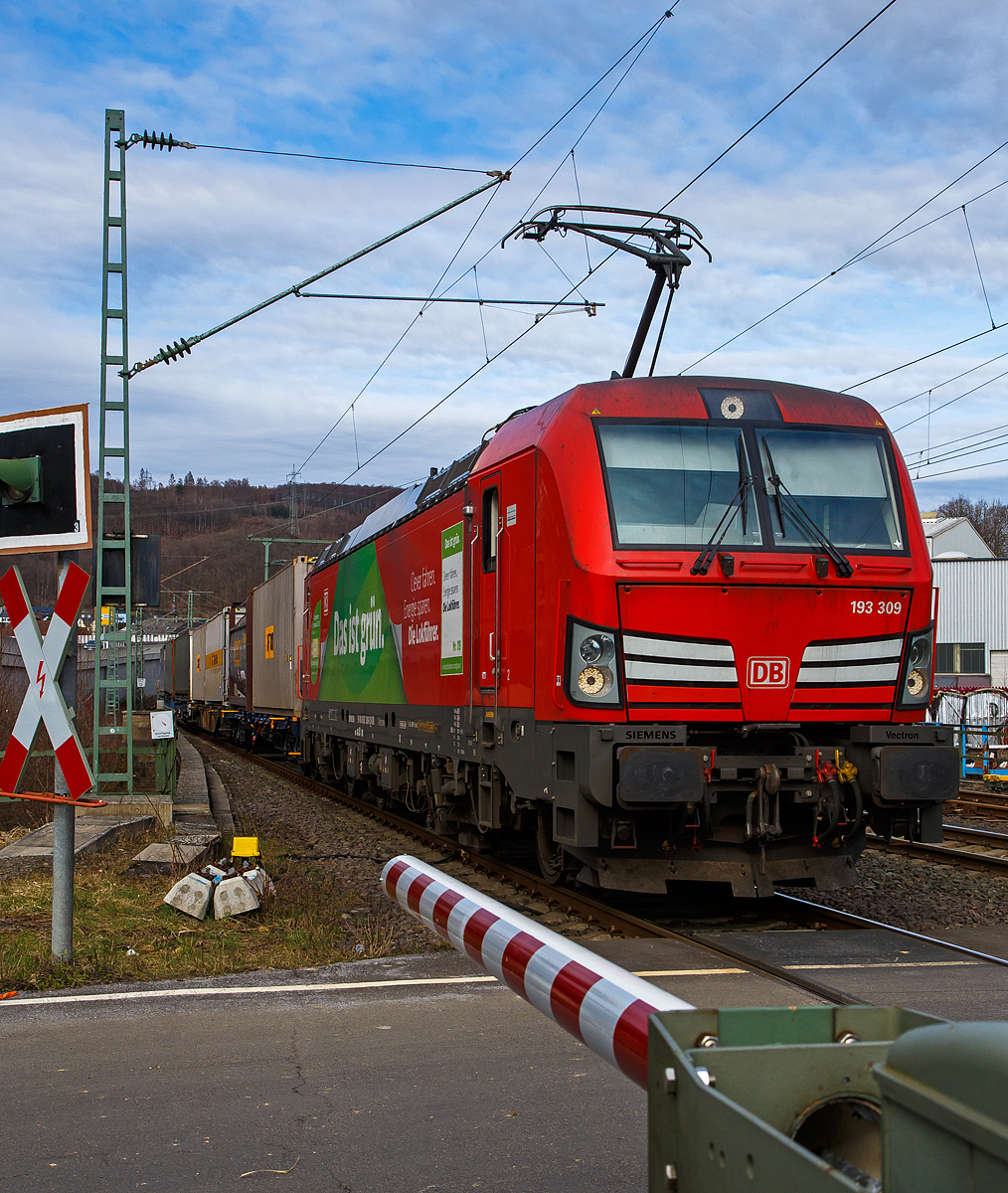 Die DB Cargo Vectron 193 309 (91 80 6193 309-2 D-DB) fährt am 20.03.2021 mit einem KLV-Zug über die Siegstrecke (KBS 460) durch Niederschelden bzw. Niederschelderhütte in Richtung Köln. Vor dem dem Bahnübergang befindet sich die Siegbrücke, die Sieg ist hier Bundes-Landesgrenze. So befinden sich hier im Bild die Lok in Rheinland-Pfalz, während die Wagen noch in Nordrhein-Westfalen sind. 

Die Vectron MS wurde 2018 von Siemens in München unter der Fabriknummer 22397 gebaut und an die DB Cargo geliefert.  Diese Vectron Lokomotive ist als MS – Lokomotive (Multisystem-Variante) mit 6.400 kW konzipiert und zugelassen für Deutschland, Österreich, Schweiz, Italien und Niederlande, sie hat eine Höchstgeschwindigkeit von 200 km/h. So ist es möglich ohne Lokwechsel vom Mittelmeer die Nordseehäfen Rotterdam oder Hamburg an zu fahren.
