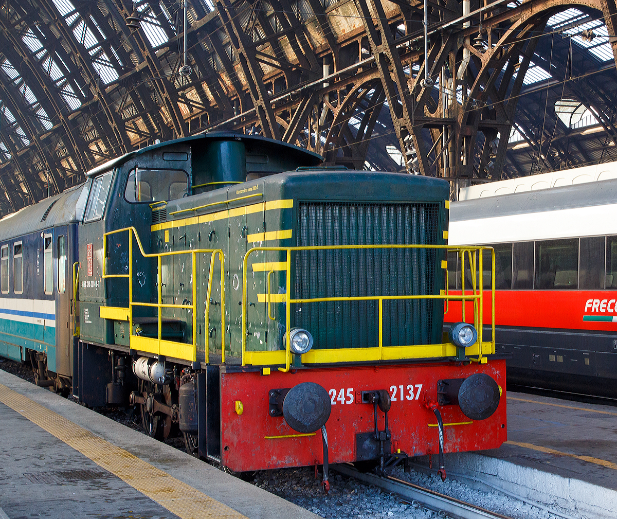
Die Dieselrangierlok D.245.337-0 (98 83 2245 337-0 I-TI) der Trenitalia (100-prozentige Tochtergesellschaft der FS), ex FS 245.2137, hängt im Bahnhof Milano Centrale am 29.12.2015 einen Zug mit IC-Wagen an.

Die FS (Ferrovie dello Stato Italiane S.p.A. / Italienische Staatseisenbahnen AG) führte 1963 die Reihe D.245 als leistungsfähigste Rangierlok ein. Die dreiachsigen Kraftpakete (Achsfolge C) wurden von verschiedenen Firmen in unterschiedlichen Formen geliefert. 

Die Formen ergeben sich aus den unterschiedlichen Serien, Herstellern und Baujahren und sind wie folgt:
245.6001–6124, Baujahre 1963 bis 1969, Cantieri Navali Riuniti/OM/Jenbacher Werke
245.0001–0058, Baujahre 1964 bis 1968, Hersteller: Antonio Badoni/OM
245.1001–1020, Baujahre 1964 bis 1968, Hersteller: OM/FIAT-Mercedes-Benz
245.2001–2020, Baujahr 1966, Hersteller: Officine Meccaniche Reggiane/Breda
245.2101–2286, Baujahre 1976 bis 1987, Hersteller: Breda/Antonio Badoni/Greco/Ferrosud/IMMER
245.8001–8003, Baujahre 1958 bis 1962, dies waren später von der FS von einem Unternehmen erworben drei Lokomotiven vom Typ Jung R42C, die später zur Hafenbahn Genua kamen. 

Die hier gezeigte Lok 245.2137 wurde 1979 von I.ME.R  S.p.a. in Carini gebaut. Die Serie 245.2101–2286 ist optisch baugleich mit der Serie 245.20 aus dem Jahr 1966, nur geringe Modifikationen wurden vorgenommen und die Kuppelstangen-Lager wurden als Rollenlager ausgeführt, anstelle der Gleitlager.
                                                                                                                                                                                                                    
Sie hat ein hydraulisches Getriebe und Stangenantrieb. Die Achsen werden mittels Kuppelstangen von einer Blindwelle (zwischen der 2. Und 3. Achse) angetrieben. Die Lok hat einen, von 440 auf 370 kW, gedrosselten 12-Zylinderdieselmotor vom Typ Breda ID36, der die Leistung auf das Voith Strömungsgetriebe (hydrostatisch), vom Typ L24. Die Dauerabtriebsleistung beträgt 275 kW. Die Kraftübertragung erfolgt über eine zwischen dem 2. und 3. Radsatz liegenden Blindwelle, Blindwellenkurbeln an den beiden Blindwellenenden und Kuppelstangen auf die Räder der Lok.
 
Technische Daten:
Spurweite:  1.435 mm (Normalspur)
Achsformel:  C
Länge über Puffer: 9.240 mm
Achsabstände:  1.500 / 2.500 mm
Eigengewicht:  46 t
Höchstgeschwindigkeit:  64 km/h (im Rangiergang 32 km/h)
Motorleistung:  370 kW
Dauerleistung:  275 kW
Treibraddurchmesser:  1.040 mm