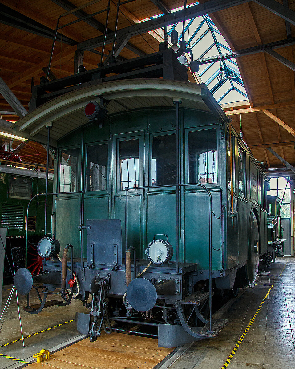 Die Drehstrom- Elektrolokomotive ex BTB De 2/2 Nr.1, ex BTB F 2/2 Nr. 1 (1902 – 1922), ex BTB E2E Nr. 1 (bis 1902), am 11.09.2022 in der Lokwelt Freilassing. Die Lok ist Eigentum des Deutschen Museums - Verkehrszentrum in M�nchen und eine Leihgabe die Lokwelt Freilassing

Dem G�terverkehr der Burgdorf-Thun-Bahn (BTB) dienten zwei Lokomotiven vom Typ F 2/2. Bis 1902 wurden sie als E2E bezeichnet, ab 1922 als De 2/2. Diese beiden ersten in der Schweiz, im Jahr 1899, gebauten elektrischen Lokomotiven (De 2/2 Nr.1 und  2) waren eine gemeinsame Konstruktion der Schweizerischen Lokomotiv- und Maschinenfabrik (SLM) in Winterthur f�r den mechanischen Teil und der Brown, Boveri & Cie. (BBC) f�r die elektrische Ausr�stung. 

Der noch nicht ausgereifte Einphasen-Wechselstrom-Betrieb konnte zur damaligen Zeit noch nicht eingesetzt werden. Deshalb beschaffte die Schweizer Burgdorf-Thun-Bahn (BTB) zun�chst f�r den reinen G�terzugbetrieb zwei dieser mit Drehstrom (Dreiphasenwechselstrom) angetriebenen Lokomotiven. Das Drehstrom-System konnte nur in einem bestimmten Geschwindigkeitsbereich effektiv arbeiten, so dass ein mechanisches Schaltgetriebe f�r zwei maximale Geschwindigkeiten notwendig war, n�mlich f�r 18 und 36 km/h.

Ab 1933 wurde der Drehstrombetrieb auf dieser Strecke eingestellt und die beiden Lokomotiven ausgemustert. Die beiden Lokomotiven sind als weltweit erste Drehstromlokomotiven f�r den Vollbahnbetrieb erhalten geblieben. Die Nr. 1 befindet in der Lokwelt Freilassing, die Nr. 2 befindet sich im Verkehrshaus der Schweiz in Luzern.

Die beiden Motoren wiesen eine Leistung von je 150 PS (110 kW) auf. Das nur im Stillstand umschaltbare Getriebe erm�glichte zwei Geschwindigkeiten, Die eine bis 18 km/h lie� auf der gr��ten Steigung von 25 ‰ eine Anh�ngelast von 100 Tonnen zu, die andere bis 36 km/h noch die H�lfte. Wobei die zul�ssige H�chstgeschwindigkeit betrug 50 km/h, so wurde in den sp�teren Betriebsjahren in Gef�llen stromlos gefahren, um diese zu erreichen. Dank der h�heren Geschwindigkeit h�tten die Lokomotiven n�tigenfalls auch im Personenverkehr Verwendung finden k�nnen.

Die beiden 19-poligen Triebmotoren sind beidseits auf einer auf einem Hilfsgestell gelagerten gemeinsamen Welle montiert. �ber ein Vorgelege wurde das Drehmoment mittels Kuppelstangen auf die beiden Achsen �bertragen. Zum Anfahren war ein f�r beide Motoren gemeinsamer Widerstand vorhanden, der mit dem in jedem F�hrerstand vorhandenen Kontroller allm�hlich ausgeschaltet wurde. Beleuchtung, Heizung und Hilfsbetriebe wurden mit einer Spannung von 100 Volt betrieben. Die Lokomotiven weisen an beiden Enden offene Plattformen auf. Die vier Schleifb�gel auf dem Dach legten sich selbstt�tig beim Wechsel der Fahrtrichtung nach hinten um. Zum Abb�geln mussten die an den B�geln angebrachten kurzen Zugseile vom Boden aus mit h�lzernen Stangen heruntergezogen und in Arretierhaken eingeh�ngt werden.

TECHNISCHE DATEN:
Baujahr: 1899, Ausmusterung1930
Spurweite: 1.435 mm (Normalspur)
Achsfolge: B
L�nge �ber Puffer: 7.800  mm
Achsabstand: 3.140 mm
Treibraddurchmesser:  1.230 mm
Dienstgewicht: 29.600 kg
H�chstgeschwindigkeit: 18 km/h / 36 km/h (stromlos bergab 50 km/h)
Stundenleistung: 300 PS (220 kW)
Stundenzugkraft: 4.400 daN
Stromsystem: 750 V, 40 Hz ∆
Anzahl der Fahrmotoren: 2
�bersetzungsstufen: 2 (f�r 18 / 36 km/h)

Die Burgdorf-Thun-Bahn (BTB) war eine Eisenbahngesellschaft in der Schweiz. Ihre Strecke von Burgdorf �ber Konolfingen nach Thun wurde als erste elektrische Vollbahn der Schweiz im Jahr 1899 dem Betrieb �bergeben. Heute ist sie Bestandteil der BLS AG