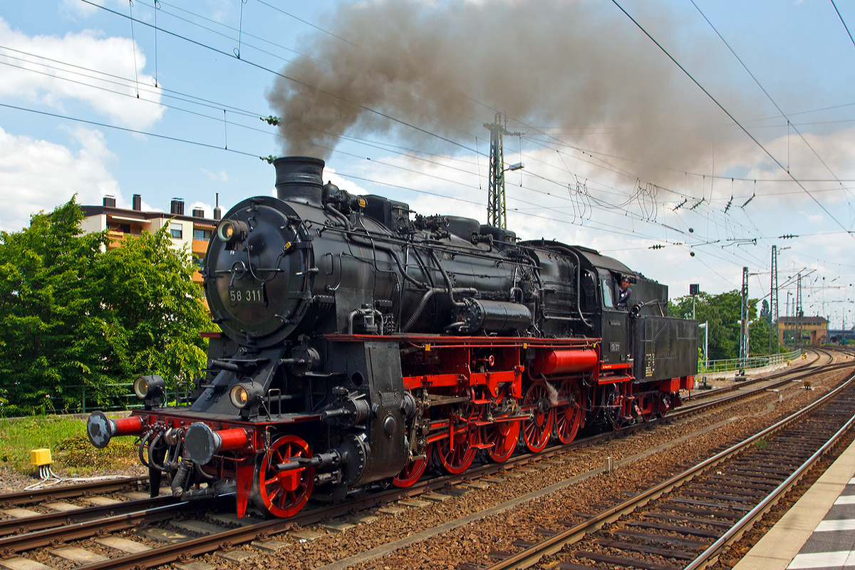 Die Dreizylinder-Güterzug-Dampflokomotive 58 311 der UEF Ulmer Eisenbahnfreunde (ex DR 58 1111-2, ex DR 58 311, ex G 12 Baden 1125), fährt sie am 31.05.2014 beim Dampfspektakel 2014 in den Hauptbahnhof Neustadt an der Weinstraße ein, um einen Personenzug anzuhängen. Sie hat die NVR-Nummer  90 80 0058 311-6 D-UEF.

Die Lokomotive 58 311 wurde 1921 von der Maschinenbaugesellschaft Karlsruhe unter der Fabriknummer 2153 als Baden 1125 (badische  G12) gebaut. Bis 1942 war sie hauptsächlich im BW Karlsruhe Rbf stationiert, kam aber dann, mit zusätzlichem Frostschutz versehen, zum Kriegseinsatz nach Oberschlesien beim BW Groschowitz. Nach einigen Irrfahrten wurde die Lok 1946 in Senftenberg wieder in Betrieb genommen und im BW Reichenbach/Vogtland einer  Gesundungs-L0  unterzogen, mit der die ärgsten Unterhaltungsmängel behoben wurden.

Nach Gastspielen in Werdau, Zwickau, Gera und Greiz kam die Lok 1960 zum BW Karl-Marx-Stadt/Hilbertsdorf, wo sie bis 1973 eingesetzt war. Die letzte Stationierung der inzwischen als 58 1111-2 umgezeichneten Lokomotive war bis 1977 das BW Aue.

Am 19.03.1977 wurde 58 311 ausgemustert, sie fuhr noch als Zuglok eines Güterzuges die damalige deutsch-deutsche Grenze, um anschließend als Lz-Fahrt zum Dampflokmuseum (DDM) in Neuenmarkt-Wirsberg, die sie gekauft hatten. Hier war sie bis zum Verkauf an die UEF im Jahre 1984 als nicht-betriebsfähiges Ausstellungsstück zu sehen.

Nach erfolgter Hauptuntersuchung konnte die Lok am 8. Juni 1985 bereits wieder zugelassen werden und kam bei den Fahrzeugparaden der DB zum 150-jährigen Jubiläum erstmals wieder vor großem Publikum zum Einsatz. Im Winter 1992/93 stand die Lok zur Fahrwerks-Hauptuntersuchung an, die im RAW Meiningen durchgeführt wurde. Seitdem war 58 311 bis zum Ablauf der Kesselfrist im Januar 2001 bei zahlreichen Sonderfahrten in ganz Deutschland, Frankreich und der Schweiz im Einsatz zu bewundern.

Seit 3. Juni 2006 ist diese Lokomotive nach langer und 
aufwändiger Hauptuntersuchung wieder betriebsbereit.

Von dieser Lokbaureihe wurden insgesamt 1478 Loks für verschiedene Bahngesellschaften gebaut.
Die Deutsche Bundesbahn musterte ihre Exemplare bereits 1953 aus. Die Deutsche Reichsbahn hatte 1968 noch 300 Maschinen im Einsatz. Bei Einführung der EDV-Nummern im Jahr 1970 wurde bei den dreistelligen Betriebsnummern im Allgemeinen eine eins an der Tausenderstelle eingefügt. Die letzten Lokomotiven wurden Ende der 1970ger-Jahre ausgemustert. 

Die gedrungene, bullig wirkende Güterzuglokomotive erreichte zwar nur eine Höchstgeschwindigkeit von 65 km/h, mit ihrem Dreizylindertriebwerk verfügte sie aber übergenügend Leistung (1.540 PS) für schwere Güterzüge im Bergland.



Technische Daten der 58 311:
Bauart:  1'E h3
Gattung:  G 56.16 (5 von 6 Achsen angetrieben / 16 t Achslast)
Spurweite:  1435 mm (Normalspur)
Länge über Puffer:  18.495 mm
Dienstgewicht:  93,6 t (ohne Tender)
Achslast:  16,3 t
Höchstgeschwindigkeit:  65 km/h
Indizierte Leistung:  1.133 kW/ 1.540 PSI
Treibraddurchmesser:  1.400 mm
Laufraddurchmesser vorn:  1.000 mm
Zylinderanzahl:  3
Zylinderdurchmesser:  570 mm
Kolbenhub:  660 mm
Kesselüberdruck:  14 bar
Tender:  pr. 3 T 20
Wasservorrat:  20,0 m³
Kohlevorrat: 6 t