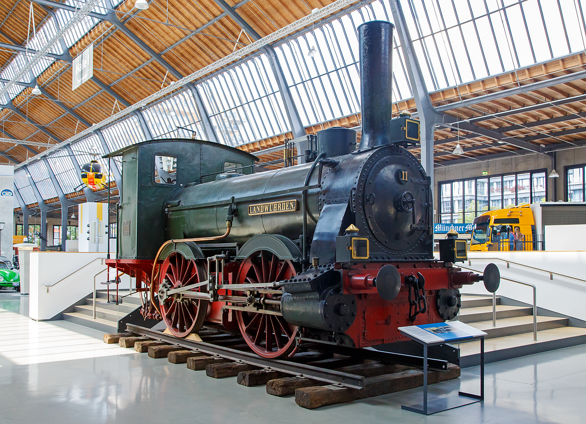Die erste von der Krauss & Companie in M�nchen gebaute Lokomotive, die Dampflokomotive „Landw�hrden“, eine Oldenburgische G 1 (am 16.06.2018) ausgestellt im Verkehrszentrum des Deutschen Museums in M�nchen. 

Die Dampflokomotive Gattung G1 wurde 1867 von Krauss & Cie. in M�nchen unter der Fabriknummer 1 gebaut und als Nr. 11 an die Gro�herzoglich Oldenburgischen Staatseisenbahnen   geliefert.  Auf der Pariser Weltausstellung von 1867 wurde die „Landw�hrden„ aufgrund ihrer fortschrittlichen Konstruktion mit der Goldmedaille ausgezeichnet. Bis 1900 war die „Landw�hrden“ als Personenlokomotive im Einsatz und legte dabei 860.000 km zur�ck. Georg von Krauss, inzwischen geadelt, kaufte sein Erstlingswerk zum Schrottpreis zur�ck, �berholte es sorgf�ltig und stiftete es als eines der ersten Gro�exponate dem Technikmuseum. Heute z�hlt sie zu den �ltesten erhaltenen Lokomotiven in Deutschland.

Die Lok der Bauart Bn2 sich durch eine besonders leichte Bauweise aus, die billig in der Anschaffung und kosteng�nstig im Unterhalt war und daher besonders f�r sekund�re Bahnen auf dem Land geeignet war, um die kleinen St�dte zu erschlie�en. Der Rahmen der Lokomotiven war als Wassertank ausgelegt, was als „System Krauss“ bekannt wurde. 

Von der Reichsbahn sollten noch 19 Maschinen als Baureihe 51.70 �bernommen werden, dazu ist es jedoch nicht mehr gekommen, weil bis zur Erstellung des endg�ltigen Umzeichnungsplans im Jahr 1925 bereits alle Lokomotiven ausgemustert waren.

TECHNISCHE DATEN:
Baujahre: 	1867–1877
Spurweite: 1.435 mm (Normalspur)
Bauart: B n2
Dienstgewicht:  23.6 t(betriebsf�hig ohne Tender)
H�chstgeschwindigkeit: 60 km/h
Leistung: 185 kW ( 252 PS)
Treibraddurchmesser: 	1.500 mm
Zylinderdurchmesser: 	355 mm
Kolbenhub:  560 mm
Kessel�berdruck: 10 bar
Rostfl�che: 0,95 m�
Verdampfungsheizfl�che: 75,0 m�
