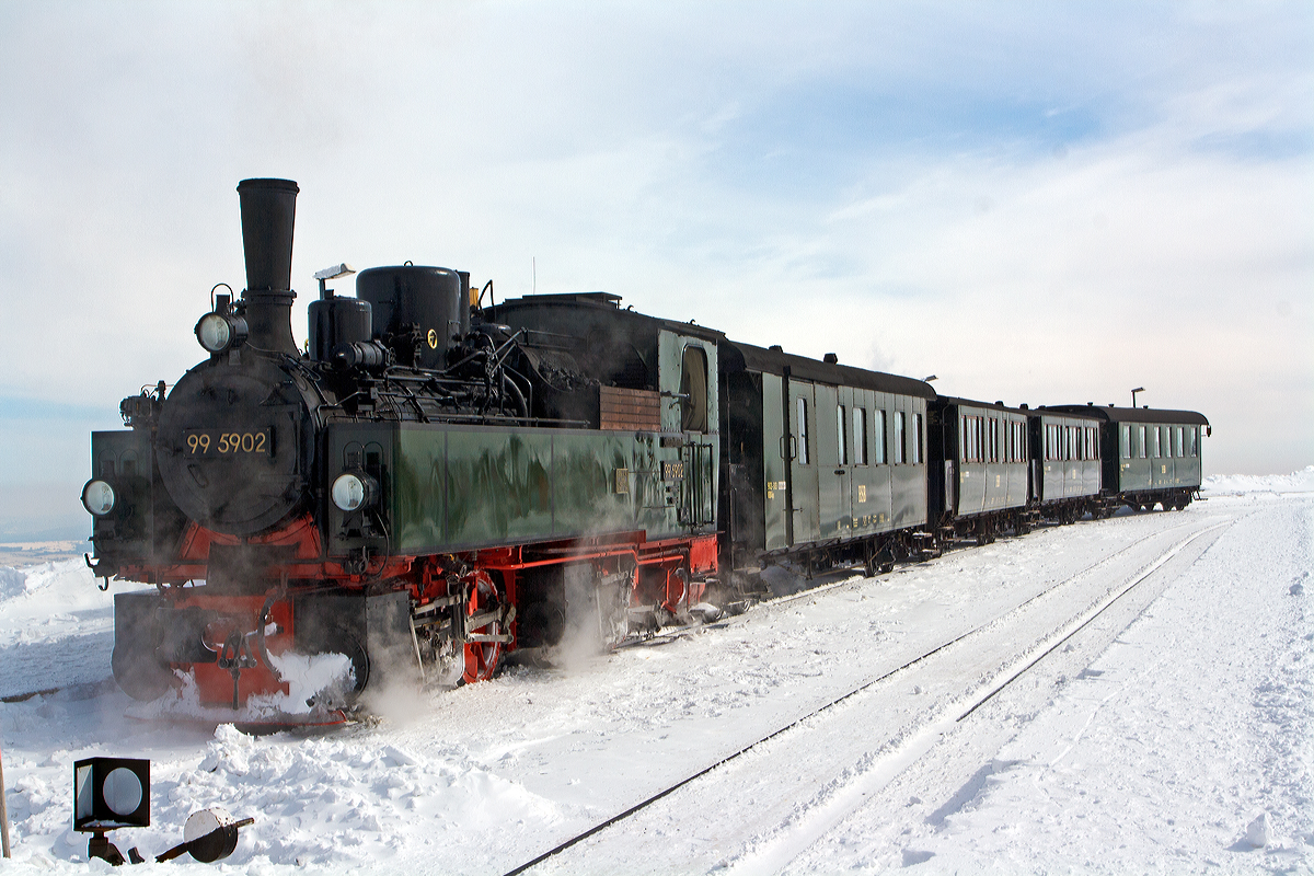 
Die Jung-Malletlok 99 5902 der HSB, ex NWE 14, ex NWE 12 (ab 1927) hat mit HSB-Traditionszug am 23.03.2013 den Brocken erreicht. Der Bahnhof Brocken (1.125 m ü.NN) ist der Kopfbahnhof am Gipfel des 1.142m hohen Brocken im Harz. Am 23.03.2013 herrschte hier ein eisiger Wind bei minus 17° Celsius.
 
Die Lok wurde 1898 von Arnold Jung Lokomotivfabrik in Jungenthal bei Kirchen a.d. Sieg unter der Fabriknummer 261 gebaut und an die NWE (Nordhausen-Wernigeroder Eisenbahn-Gesellschaft) als Nr. 14 geliefert ab 1927 wurde sie zur NWE 12.