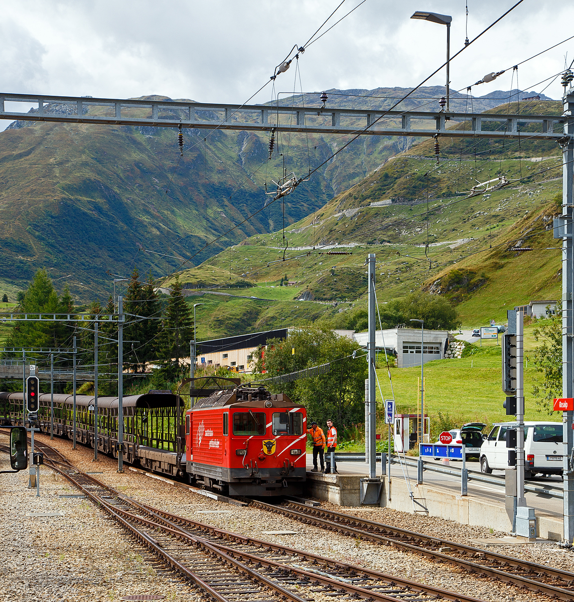 Die letzte, die Tunnellokomotive MGB Ge 4/4 III - 81 „Wallis“ der Matterhorn-Gotthard-Bahn ex FO Ge 4/4 III - 81, steht am 07.09.2021mit einem Furka-Autoverladezug beim Bahnhof Realp (1.538 m ü. M.). 

Die Ge 4/4 III ist eine vierachsigen schmalspurige (1.000 mm) reine Adhäsions-Elektrolokomotive. Für die Beförderung der Autozüge durch den Furka-Basistunnel beschaffte die FO Furka-Oberalp-Bahn 1979 zwei vierachsige Schmalspurlokomotiven. Die Lokomotiven stellten eine Weiterentwicklung der RhB Ge 4/4 II der Rhätischen Bahn dar. Daher erhielten sie die Bezeichnung Ge 4/4 III, obwohl die FO keine weiteren Ge 4/4 besaß. Die Lokomotiven haben eine Leistung von 1.700 kW, eine Höchstgeschwindigkeit von 90 km/h und werden unter einer Fahrdrahtspannung von 11 kV, 16,7 Hz eingesetzt. Die Fahrzeuge sind die einzigen Streckenlokomotiven der MGB, die keinen Zahnradantrieb besitzen. Die MGB Ge 4/4 III - 81 „Wallis“ ist noch vorhanden, die Schwesterlok Ge 4/4 III - 82 „Uri“ wurde 2015 außer Betrieb gesetzt und als Ersatzteilspender für die 81 verwendet. Nachdem sie länger abgestellt war, erfolgte der Abbruch im November 2017. Einige Teile wurden für den Erhalt der Lok 81 eingelagert. Eines der beiden Urner Wappen von Lok 82 ist nun an einer Stirnseite der Schwesterlok 81 befestigt (wie hier im Bild zu sehen).

Die Lokomotive besitzt einen gesickten selbsttragenden Lokomotivkasten. Aus statischen Gründen musste die Einstiegstüre des Führerstandes nach hinten versetzt werden. Die Seitenwände haben keine Montageöffnung, sondern die ganze elektrische Innenausrüstung ist über die drei Dachluken eingebaut. Die Luftansaugöffnungen befinden sich auf dem Dach und sind für die Ausfilterung von Bremsstaub und feinem Flugschnee ausgelegt. Als Antrieb kam ein SLM-Schiebelagermotor zum Einsatz. Es handelt sich dabei um eine verbesserte Bauform eines Tatzlager-Antriebes, wobei sich der Motor eben auf kein festes, sondern ein seitenbewegliches Lager auf der Achse abstützt. Die beiden Schiebelager ermöglichen eine Axialverschiebung des Triebradsatzes. Somit wird der Radsatz in Querrichtung von der Masse des Motors entkoppelt. Die Schaltung des Hauptstromkreises entspricht weitgehend der RhB Ge 4/4 II, wobei im Traktionsstromrichter durch den technischen Fortschritt einige Vereinfachungen möglich waren. Auch in der Steuerung waren nur minimale Anpassungen erforderlich. Es ist deshalb auch möglich, mit der RhB Ge 4/4 II in Vielfachsteuerung zu verkehren
. 
Die Lokomotive besitzt für sich und die Autozug-Komposition eine Druckluftbremse. Diese ist mit einer Lufttrockungseinrichtung des Systems Lugart ausgerüstet, damit Bremsstörungen infolge der zum Teil doch harten Klimawechsel innerhalb und außerhalb des Tunnels vermieden werden können. Damit sie mit den übrigen Fahrzeugen verkehren kann, ist auch eine Vakuumbremse eingebaut. Als Handbremse bzw. Feststellbremse ist eine mit der Druckluft gekoppelte Federspeicherbremse eingebaut. 

TECHNISCHE DATEN:
Nummerierung: 81, 82 
Spurweite: 1.000 mm (Meterspur)
Achsformel: Bo'Bo'
Hersteller: SLM Winterthur /  BBC (technischer Teil)
Länge über Puffer: 12.900 mm
Höhe: 3.870 mm
Breite: 2.680 mm
Höchstgeschwindigkeit: 90 km/h
Dienstgewicht: 50 t
Stundenleistung: 1.700 kW
Treibraddurchmesser:  1.070 mm (neu)
Anzahl der Motoren: 4
Steuerung:  Thyristor
Stromsystem: Einphasenwechselstrom 11.500 V / 16,7 Hz,

Geschichte:
Mit dem Bau des Furka-Basistunnels und dem Beschluss, ihn auch für den Autoverlad zu benutzen, war die Beschaffung der Autozugkompositionen zu evaluieren. Am Schluss blieb aus wirtschaftlichen Gründen eine konventionelle Lösung als Pendelzug mit einer Lok und Steuerwagen und dazwischen eingereihten Transportwagen. Als notwendige Transportkapazität wurden für Spitzenzeiten 100 Autos pro Stunde und Fahrrichtung angenommen, was zur Beschaffung zweier Kompositionen und damit dieser zwei Lokomotiven führte. 

Es wurden mehrere Varianten des Triebfahrzeugeinsatzes überprüft, darunter die Verwendung vorhandener Fahrzeuge mit und ohne Modernisierung. Dabei kam man zum Schluss, dass ein reines Adhäsionsfahrzeug der Bauart der RhB Ge 4/4 II die im Unterhalt kostengünstigste Lösung sei, wenn auch in der Anschaffung die teuerste Variante. 

Die FO ließ sich 1977 von der Industrie zwei Lokomotiven des Typs der RhB Ge 4/4 II offerieren, allerdings mit verstärkter elektrischer Bremse. Die Anbieter schlugen eine überarbeitete Lokomotive vor, die günstiger war, als die Ge 4/4 II vormals gekostet hatte. Die Änderungen gegenüber dem Referenzfahrzeug bezogen sich vor allem auf die Kastenbauform und den Antrieb. Die FO ging auf dieses Angebot ein. Zwischen der Ablieferung 1980 und der Inbetriebnahme des Furka-Basistunnels wurden die Lokomotiven an die RhB vermietet, die sie mit Schnellzügen auf der Albulalinie einsetzte. Seit 1982 werden sie ausschließlich für die Autozüge zwischen Oberwald VS und Realp UR verwendet. 

Eine Zugkomposition besteht aus:
An der Spitze des Zuges befindet sich immer auf der Seite Realp die Lokomotive. Es folgt ein Rampenwagen (Auffahrwagen) Sklv 4801 bis 4807, dann sechs Verladewagen (Sklv 4811 bis 4827), wieder ein Rampenwagen und als Abschluss ein Steuerwagen (BDt 4361bis 4363) auf der Seite Oberwald. Die Rampen- und Verladewagen sind mit Kuppelstangen fest zu einem Blockzug verbunden. Die Rampenwagen wiederum sind gegen die Lok und den Steuerwagen mit einer automatischen Kupplung +GF+, Typ Brünig, ausgerüstet.