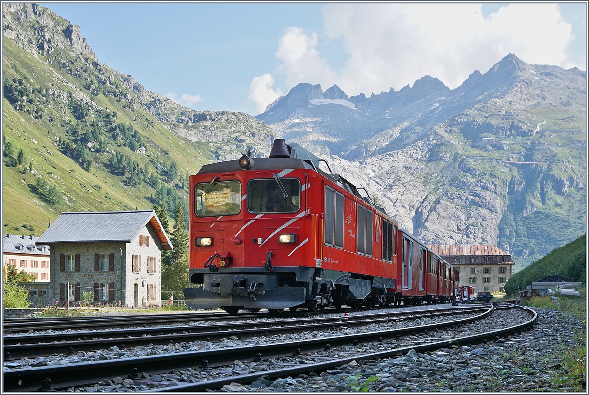 Die MGB HGm 4/4 61 (Baujahr 1967) wartet mit ihrem Personenzug 325 in noch schattigen Bahnhof von Gletsch auf die Weiterfahrt nach Oberwald.

31. August 2019