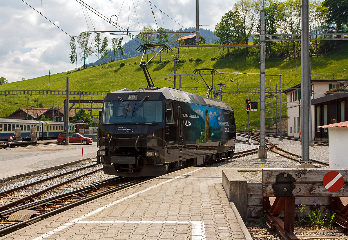 
Die MOB Ge 4/4 8003 (mit Werbung für das Menuhin-Festival 2012 „Air“ in Gstaad) am 28.05.2012 beim Manöver (Umsetzen) im Bahnhof Zweisimmen.

Die Lok wurde 1994 von der Schweizerische Lokomotiv- und Maschinenfabrik (SLM) in Winterthur gebaut, die elektrische Ausrüstung ist von ABB Verkehrssysteme AG. Die Lok wurde 2019 an die Rhätische Bahn (RhB) verkauft und wird dort zur Ge 4/4 653 umgebaut. Die GE 4/4 sind die leistungsstärksten schweizerischen Gleichstrom-Triebfahrzeuge. Die Maschinen der MOB (Montreux–Berner Oberland-Bahn) haben übrigens keine Eigennamen oder Wappen, sie tragen nur die Betriebsnummer.

Die vier 1994 von SLM und ABB für die MOB gebauten Ge 4/4 ähneln sowohl optisch als auch mechanisch den Ge 4/4 der Bière-Apples-Morges-Bahn (BAM) und den Ge 4/4 III der Rhätischen Bahn (RhB). Der elektrische Teil musste jedoch dem Betrieb ab Fahrleitung mit 900 V Gleichspannung angepasst werden und eine allfällige Umrüstung auf Zweisystem-Betrieb mit zusätzlich 15 kV 16,7 Hz berücksichtigen. Der Betrieb mit Wechselspannung wäre notwendig gewesen, wenn die GoldenPass-Linie mit einer dritten Schiene bis Interlaken verlängert worden wäre. So ist im Lokkasten bereits der Platz für einen Transformator für den Betrieb bei 15 kV mit 16 2/3 Hz Wechselstrom vorgesehen, ebenso lässt sich ein dritter Pantograph nachrüsten.

Die Lok ist mit vier Schnellschaltern ausgerüstet, die über Drosseln die wassergekühlten Stromrichter versorgen. Die Eingangsspannung der Wechselrichter kann von 630 bis 1080 Volt variieren, für den Zweispannungsbetrieb hätte die Zwischenkreisspannung 1350 Volt betragen. Dies erforderte eine Anpassung der Fahrmotorwicklung gegenüber den RhB-Loks, die für eine Zwischenkreisspannung von 2100 bis 2800 Volt ausgelegt sind. Der mechanische Teil des Fahrmotors ist baugleich mit demjenigen der RhB-Motoren.

Die Loks haben eine Leistung von 2000 kW und erreichen eine Höchstgeschwindigkeit von 120 km/h, die jedoch im Normalbetrieb mangels geeigneter Strecken nicht erreicht wird. Wegen der relativ geringen Spannung sind sehr hohe Stromstärken erforderlich. Daher fahren die Loks der Montreux–Berner Oberland-Bahn (MOB) immer mit zwei Stromabnehmern am Fahrdraht. Zudem sind die Stromabnehmer mit drei statt den üblichen zwei Schleifleisten versehen, was man hier im Bild auch gut sehen kann.

Möglich ist auch die Vielfachsteuerung mit den MOB GDe 4/4, was erst erforderlich ist, wenn mehr als sechs Panoramawagen zu befördern sind. Dies ist bisher nur vereinzelt vorgekommen.

Die Loks hatten (wie im Bild auch zu sehen) Mittelpuffer mit einer Schraubenkupplung, ab 2017 wurden die drei bei der MOB verbliebenen Loks auf automatische Mittelpufferkupplung (Schwab-Kupplung) umgebaut. Seit 2020 sind die verbliebenen 3 Lokomotiven mit allen Fahrzeugen Steuerwagen sowie den Triebwagen mit Schwab-Automatikkupplung in Vielfachsteuerung kompatibel und

TECHNISCHE DATEN:
Gebaute Anzahl: 4, die Ge 4/4 8003 wurde 2019 an die RhB verkauft. 
Hersteller mech. Teil: SLM, Winterthur 	  	
Elektr. Ausrüstung: ABB Verkehrssysteme AG
Spurweite: 1.000 mm (Schmalspur)
Achsfolge:	Bo'Bo'
Länge über Puffer: 16.100 mm 
Treibraddurchmesser: 	1.070 mm
Breite max.: 2.800 mm
Höhe : 3.860 mm 	  	
Dienstgewicht: 63 t
Anzahl der Fahrmotoren:  4
Maximale Leistung am Rad:	2.400 kW 	 
Dauerleistung am Rad: 2.000 kW 	  	 
Dauerzugkraft am Rad: 150 kN
Anfahrzugkraft am Rad:  200 kN
Höchstgeschwindigkeit: 120 km/h 	  
Anhängelast bei 45 km/h und 73‰ Steigung: 170 t
Anhängelast bei 80 km/h und 25‰ Steigung:	300 t
Stromsystem: 900 V DC (Gleichstrom)
Stromübertragung: 2 Einholmstromabnehmer mit je 3 Schleifleisten
