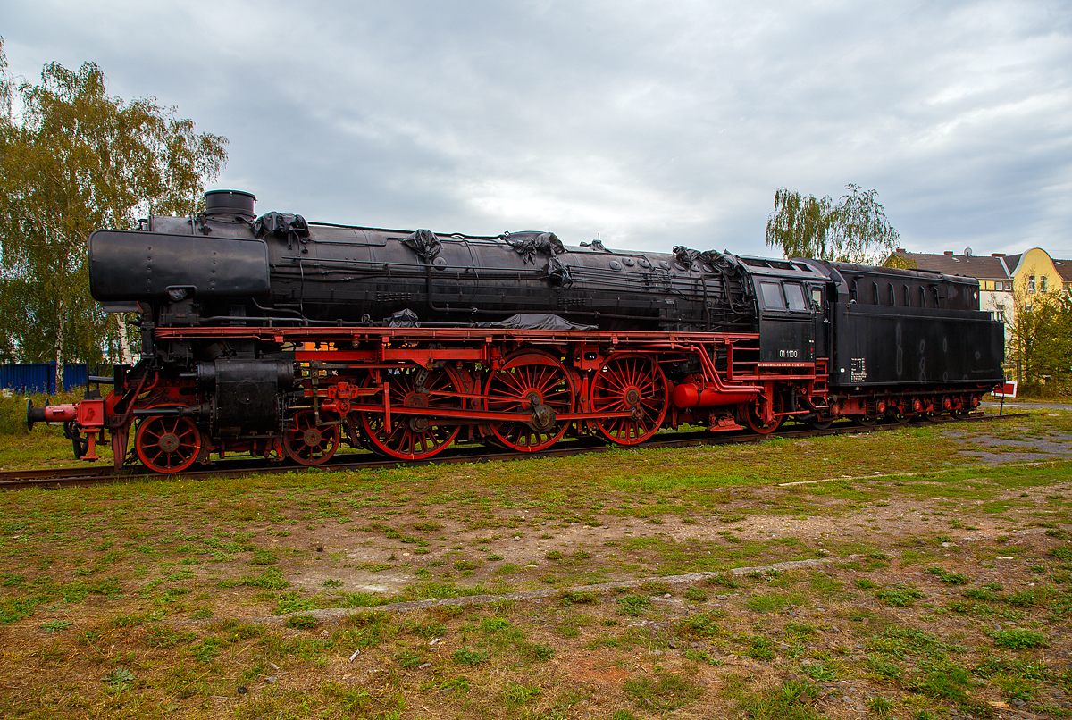 Die ölgefeuerte Dreizylinder-Schnellzug-Dampflokomotive 01 1100, ex DB 012 100-4, steht am 04.09.2020 im DB Museum Koblenz-Lützel. Die Lok wurde 1940 von der BMAG (Berliner Maschinenbau-Actien-Gesellschaft vormals L. Schwartzkopff), in Berlin unter der Fabriknummer 11356 gebaut und wurde an die Deutsche Reichsbahn geliefert. Am 31. Mai 1975 wurde die Lok bei der DB letztmalig planmäßig eingesetzt, zum 01.06.1975 erfolgte die z-Stellung und am 26.06.1975 die ausmusterung im Bw Rheine. 

Die Dampflokomotiven der Baureihe 01.10 waren von der Deutschen Reichsbahn im Rahmen des Einheitsdampflokomotiv-Programms beschaffte Schnellzuglokomotiven und eine Weiterentwicklung der Baureihe 01.

Die Deutsche Reichsbahn benötigte für ihr Netz schnellfahrender D- und FD-Züge leistungsstarke Dampflokomotiven mit einer Höchstgeschwindigkeit von 150 km/h. Es sollten Züge von 550 Tonnen in der Ebene mit 120 km/h sowie Züge von 425 Tonnen auf einer Steigung von 4 ‰ noch mit 100 km/h befördert werden.

Die bereits vorhandenen Lokomotiven der Baureihen 01 und 03 waren zwar nur für 120 bzw. 130 km/h zugelassen, konstruktiv jedoch bereits auf eine Höchstgeschwindigkeit von 140 km/h ausgelegt. Die starken Zuckbewegungen durch das Zweizylindertriebwerk dieser Baureihen ließen die höhere Geschwindigkeit jedoch nicht zu. Auch im Hinblick auf bessere Anfahreigenschaften entschied man sich zur Beschaffung von Maschinen mit laufruhigeren Dreizylindertriebwerken, dies ebenfalls wieder mit einfacher Dampfdehnung.

Zur Verringerung des Fahrwiderstandes wurden die Fahrzeuge mit einer bis 400 mm über Schienenoberkante heruntergezogenen Stromlinienverkleidung ausgerüstet. Durch diese konnte, wie Versuche mit der Baureihe 03 zeigten, die Zugleistung bei Geschwindigkeiten von 140 km/h um 48 ‰ gesteigert werden. Diese Mehrleistung bei höheren Geschwindigkeiten wurde bei der Baureihe 01.10 allerdings teilweise wieder durch die schlechtere Dampfversorgung des Dreizylindertriebwerkes im Vergleich zum Zweizylindertriebwerk aufgezehrt.

Bei einem berechneten Bedarf von 400 Lokomotiven wurden 1939 zunächst 204 Stück bei allen großen Lokomotivfabriken in Deutschland bestellt. Kriegsbedingt wurden jedoch nur 55 Lokomotiven ausgeliefert. Alle Maschinen stammten von Schwartzkopff (BMAG). 1944 wurden alle Lokomotiven wegen der Kriegsereignisse nach Westdeutschland verlegt. Nach dem Zweiten Weltkrieg befanden sich die Maschinen in einem desolaten Zustand. Vielfach fehlten Teile der Stromlinienverkleidung und die Kessel aus der als Kesselbaustoff nicht alterungsbeständigen Stahlsorte St 47 K zeigten erste Ermüdungserscheinungen. Am 20. Juni 1945 wurde die Ausmusterung über die gesamte Baureihe verfügt. Die Lokomotiven waren bis zu diesem Zeitpunkt jeweils weniger als 500.000 Kilometer gefahren. Aufgrund des herrschenden Lokomotivmangels nach dem Krieg griff man im Weiteren doch wieder auf die Baureihe zurück, einige Maschinen mit kleineren Schäden wurden vorläufig instandgesetzt.

Der Großteil der Lokomotiven blieb jedoch bis 1949 abgestellt. Im selben Jahr entschloss man sich, sämtliche Lokomotiven, bis auf eine (01 1067), die endgültig ausgemustert blieb, einer Aufarbeitung zu unterziehen. Im Rahmen dieser Aufarbeitung wurde die Stromlinienverkleidung von Lokomotive und Schlepptender vollständig entfernt und es wurden Windleitbleche der sogenannten Bauart Witte montiert. 

Ungelöst blieb das Problem der Kessel aus St 47 K, bei dem Schäden durch Ermüdungen und als Folge von Schweißungen auftraten. Da man im Betrieb auf die Maschinen nun nicht mehr verzichten konnte, entschloss man sich 1953, neue geschweißte Hochleistungskessel mit Verbrennungskammer in Auftrag zu geben. Diese wurden zwischen 1953 und 1956 bei Henschel in Kassel beschafft und im AW Braunschweig zusammen mit einer Mischvorwärmeranlage nach Bauart Heinl eingebaut. Die Verdampfungsleistung der über einen größeren Anteil an Strahlungsheizfläche verfügenden Neubaukessel war trotz geringerer Rost- und Gesamt-Verdampfungsheizfläche um rund 10 % höher als bei den Altbaukesseln. Bei den Maschinen mit Ölfeuerung waren Dampfverbräuche bis hinunter zu 5,8 kg/PSih möglich. 

1956 erhielt die 01 1100 zusammen mit dem neuen Kessel versuchsweise eine Ölhauptfeuerung. Mit dieser konnte die Leistung der Lok nennenswert erhöht werden, außerdem konnte die Ölfeuerung elastischer geregelt und damit den Betriebsverhältnissen besser angepasst werden. Die Maschinen waren daher wirtschaftlicher als kohlegefeuerte Dampfloks. Die Arbeit des Heizers wurde durch das Wegfallen des Kohleschaufelns erleichtert, da die Brennstoffzufuhr nun durch einen Schieber reguliert wurde. Der Heizer konnte überdies den Lokführer nun besser bei der Streckenbeobachtung unterstützen.

Verfeuert wurde das seinerzeit als Abfallprodukt vorhandene Schweröl (Bunker-C). Aufgrund der positiven Erfahrungen entschloss man sich 1957, weitere 33 Lokomotiven dieser Baureihe auf Ölfeuerung umzubauen. 1968 erhielten die kohlegefeuerten Lokomotiven bei der Umstellung auf das EDV-konforme Nummernsystem die Baureihenbezeichnung 011, die ölgefeuerten die 012.

Am 31. Mai 1975 wurden die letzten Maschinen der Baureihe, die teilweise Monatsleistungen von über 25.000 Kilometern und Gesamtkilometerleistungen von deutlich über 3,5 Millionen Kilometern erbracht haben, vom Bw Rheine letztmals planmäßig eingesetzt und anschließend unter Anteilnahme von Eisenbahnfreunden ausgemustert.

TECHNISCHE DATEN: 
Ausmusterung:  1975
Bauart:  2’C1’ h3
Gattung:  S 36.20 (Schweiz A 3/6)
Spurweite:  1.435 mm (Normalspur)
Länge über Puffer:  23.130 mm
Höhe:  4.550 mm
Leergewicht (ohne Tender):  101 t
Gewicht Lok und Tender: 177 t
Radsatzfahrmasse:  20 t
Höchstgeschwindigkeit:  vorwärts 150 km/h, rückwärts 50 km/h
Indizierte Leistung:  1.817 kW (ca. 2.470 PS)
Treibraddurchmesser:  2.000 mm
Laufraddurchmesser vorn: 1.000 mm 
Laufraddurchmesser hinten:  1.250 mm
Steuerungsart:  Heusingersteuerung mit Hängeeisen
Zylinderanzahl: 3
Zylinderdurchmesser:  500 mm 
Kolbenhub:  660 mm
Kesselüberdruck:  16 bar
Anzahl der Heizrohre:  119 
Anzahl der Rauchrohre: 44
Heizrohrlänge: 5.000 mm
Rostfläche:  3,96  m² 
Strahlungsheizfläche: 22 m²
Überhitzerfläche:  96,15 m² 
Verdampfungsheizfläche: 206,51 m² 
Tender:  2’3 T 38
Wasservorrat:  38,0 m³
Brennstoffvorrat:  13,5 t Schweröl
Zugheizung: Dampf
