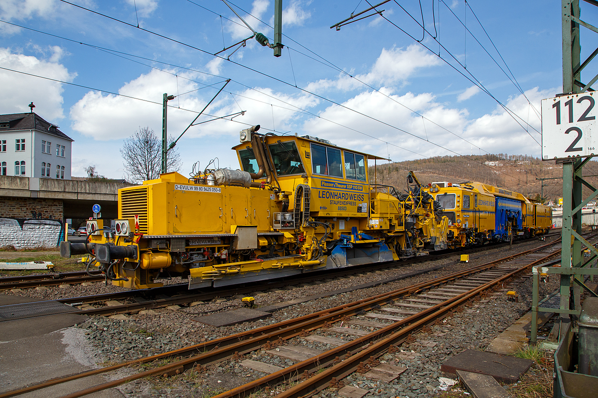 Die Plasser & Theurer Universalstopfmaschine UNIMAT 09-4x4/4S (Kombinierte Gleis- und Weichenstopfmaschine), Schweres Nebenfahrzeug Nr. D-EVULW 99 80 9424 022-1 „Stuifenexpress“  588627, und die Plasser & Theurer Schnellschotterplaniermaschine SSP 110 SW, Schweres Nebenfahrzeug Nr. D-EVULW 99 80 9425 050-8 „Staufenexpress“ 88503, ex 97 16 40 574 17-6, beide von der Leonhard Weiss GmbH & Co. KG (Göppingen) fahren am 09.04.2021 als Zugverband durch Niederschelden in Richtung Siegen. Hier passieren sie gerade den Bü 343 (Km 112,183 der Siegstrecke KBS 460).

Die Stopfmaschine UNIMAT 09-4x4/4S wurde 2017 von Plasser & Theurer unter der Maschinen-Nr, 6559 gebaut. Der Schotterpflug SSP 110 SW wurde 2002 von  Plasser & Theurer unter der Maschinen-Nr,   716 gebaut.