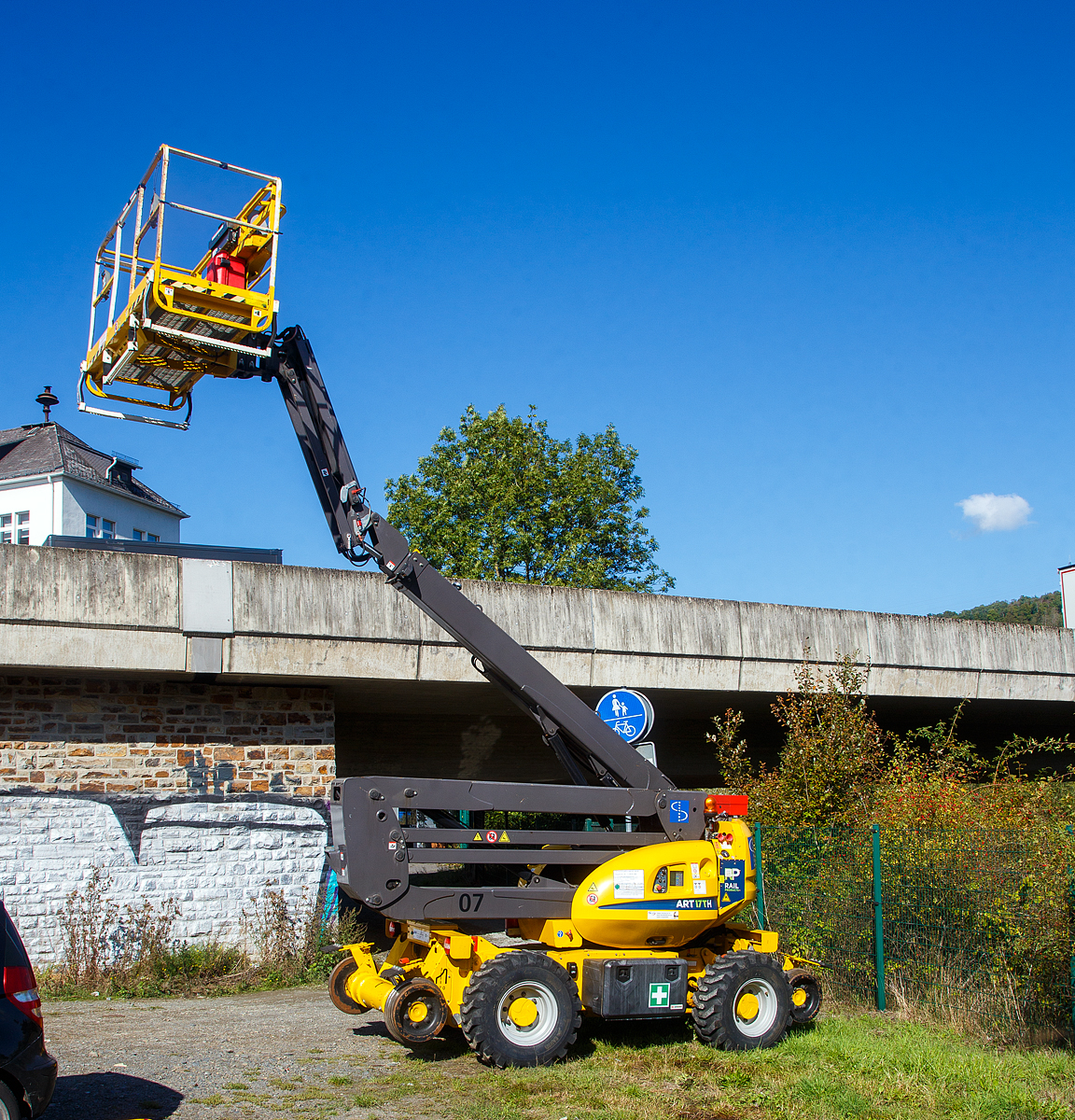 Die Rail Products Zweiwegehubarbeitsbühne ART 17 TH (Manitou), Schienengebundenes Gerät Registier-Nr. G 9936 066, der Spitzke SE (Großbeeren), abgestellt am 30.09.2022 in Niederschelderhütte an der Siegstrecke beim Bahnübergang Charlottenhütte.

Zweiwegehubarbeitsbühne hat eine maximale Arbeitshöhe von 16,25 m mit einer 400 kg belastbaren Bühne die um 360° drehbar ist. Die Reichweite mit vollausgefahrenem Teleskoparm beträgt 8,95 m, dabei ist noch eine Gleisüberhöhung bis zu 120 mm mit einer Volllast von 400 kg auch bei 90°-Schwenkung zu Seite möglich. 

Funktionsmerkmale:
• Großer Arbeitskorb mit drei Zugangspunkten
• Allradbremse auf Straße und Schiene
• Allradantrieb auf Straße und Schiene
• Vierrad-Feststellbremse
• Volle Stabilität bei 180 mm Neigung im Arbeitsmodus und 200 mm Überhöhung im Fahrmodus
• Vollvandalenschutz / vollständiger Vandalenschutz

Bei der Konstruktion, Entwicklung und Herstellung arbeitet Rail Products eng mit der Fa. Manitou zusammen, so ist auch hier das Grundfahrzeug ein Manitou. Als Basis für diese einzigartige Schienenarbeitsbühne dient der Manitou 160 ATJ PA RC Plus, eine leistungsfähigste Gelenkarbeitsbühne auf dem Markt. Mit 400 kg Korbtraglast sowie einer Steigfähigkeit von bis zu 40 %, einer Arbeitshöhe von 16.4 m und der seitlichen Reichweite von bis zu 8.94 m ist die vollgeländegängige Allradbühne eine effiziente und leistungsfähige Schienenarbeitsbühne im Markt. Die Bühne kann mit vielen optionalen Features auf die Bedürfnisse unserer Kunden abgestimmt werden. Neben den Standardversionen für Normal- oder Schmalspur ist sie auch mit Dualer Fahrspur, welche mechanisch oder hydraulisch verstellt werden kann, erhältlich. Druckluft und Wasserzufuhr in den Korb, die Ausrüstung mit einem Notstromaggregat, die Ergänzung durch einen Arbeitsanhänger sowie ein Höhenmesssystem inkl. Datenaufzeichnung sind nur einige der vielfältigen optionalen Ausstattungsmöglichkeiten.

TECHNISCHE DATEN:
Hersteller: Rail Products Ltd, Carluke (GB)
Baujahr: 2019
Fabriknummer: 0043191
Spurweite: 1.435 mm 
Länge über Alles: 6.930 mm
Höhe in Transportstellung:  2.700 mm
Achsanstand: 3.410 mm (Schiene) / 2.200 mm (Straße)
Laufraddurchmesser: 470 mm (neu)
Bodenfreiheit: 425 mm
Eigengewicht: 12,3 t
Nutzlast: - t
Anhängelast: -  t
Kleinster befahrbarer Gleisbogen: R = 80m
Bremse: Hydrost. Bremse
Höchstgeschwindigkeit (Schiene):  12 km/h (Straße 5 km/h)
Arbeitsgeschwindigkeit max. (Schiene):  1 km/h (mit gehobener Bühne)
Anmerkung: Darf nur im gesperrten Gleis o. im Baugleis verwendet werden.
Motorart: wassergekühlter 4-Zylinder-Dieselmotor mit Direkteinspritzung und Turbolader
Motortyp: Kubota V2403-M  
Motorleistung: 46 PS
Arbeitshöhe: 16,25 m (Bodenhöhe der Plattform 14,40 m)
Max. Reichweite: 8,95 m
Korbgröße: 2,30 x 0,93 m
Hebezeit : 40 sek
Korbtragfähigkeit: 400 kg (3 Personen)

Anmerkung: Alle vier Räder angetrieben bzw. gebremst, sowie Allradlenkung.  

Quelle: Rail Products,  Spitzke und Anschriften
