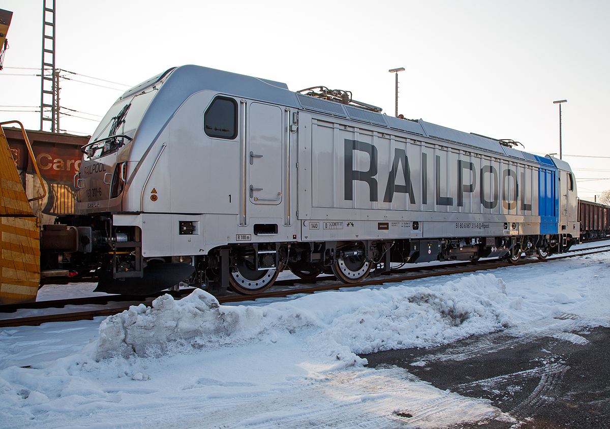 Die RAILPOOL 187 311-6 (91 80 6187 311-6 D-Rpool), eine Bombardier TRAXX F140 AC3 LM auch bekannt als Last-Mile-Lokomotive, abgestellt am 22.01.2016 beim ICE-Bahnhof Montabaur.

Die TRAXX F140 AC3 LM wurde 2016 von Bombardier gebaut. Nach meiner Sichtung hat die Lok die Zulassung für Deutschland und Österreich. Für Ungarn und Rumänien sind die Zulassungen noch nicht erteilt (H und RO sind durchgestrichen).

Die TRAXX F140 AC LM ist eine vierachsige Lokomotive mit einer Leistung von 5.600 kW für den grenzüberschreitenden Einsatz. Die Lokomotive befördert hauptsächlich Güterzüge auf den europäischen Hauptstrecken, die mit 15 kV oder 25 kV elektrifiziert sind. Die Höchstgeschwindigkeit beträgt 140km/h. Die Lokomotiven können in gemischter Mehrfachtraktion mit BR185 und BR186 eingesetzt werden.

Mehr als 2.140 TRAXX-Lokomotiven wurden bisher weltweit verkauft. Ihr modularer Aufbau macht sie so einzigartig: In rund 70 Prozent ihrer Bauteile sind alle TRAXX-Loks identisch. Sie sind 18,9 Meter lang, haben die gleichen Drehgestelle, Traktionsmotoren, Führerstände und Kommunikationssysteme. TRAXX-Lokomotiven fahren je nach Bedarf grenzüberschreitend und sind in 19 Ländern zugelassen. Die Baureihe 187 ist die erste Variante der Traxx-3-Reihe. Die interne Bezeichnung von Bombardier für die Baureihe 187 lautet Traxx F140 AC3 LM.

Die Endmontage der Lokomotiven erfolgt im Bombardier-Werk Kassel, einem Teil des ehemaligen Henschel-Werkes. Die Wagenkästen kommen aus Wrocław (Polen), die Drehgestelle aus Siegen. Antriebs-, Steuerungs- und Sicherheitssysteme werden in Mannheim und Hennigsdorf sowie in Västeras (Schweden) hergestellt.

Die Baureihe 187 ( Traxx F140 AC3 LM) wurde von Bombardier auf der Messe Transport und Logistik im Mai 2011 in München erstmals präsentiert. Die BR 187 ist eine für 15 kV 16,7 Hz und 25 kV 50 Hz Wechselstrom ausgerüstete Lokomotive, die mit einem 180 kW starken Dieselhilfsmotor  vom Typ Deutz TCD2013 4V ausgestattet ist, um auch Streckenabschnitte ohne Oberleitung (Last Mile) befahren zu können. Im Dieselbetrieb werden alle vier Fahrmotoren betrieben; die Anfahrzugkraft ist dabei genauso hoch wie bei elektrischem Betrieb. Ohne Anhängelast kann eine Lokomotive der Baureihe 187 mit ihrem Dieselmotor eine Höchstgeschwindigkeit von 60 km/h erreichen; ein 2.000 Tonnen schwerer Zug kann noch auf 40 km/h beschleunigt werden. Der Diesel-Hilfsmotor verfügt über einen Hubraum von 7.150 cm³ und erfüllt die Stage-IIIB-Abgasnorm. Der Tankinhalt von 400 Litern reicht für bis zu acht Stunden Dieselbetrieb, kurze Strecken können auch ausschließlich mit der eingebauten Batterie zurückgelegt werden. Der Übergang von elektrischer Traktion zu Dieseltraktion kann während der Fahrt erfolgen. Für den Rangierbetrieb ist eine Funkfernsteuerung erhältlich.

Mit der Last Mile Funktion gehört der Wechsel der von elektrischer Lokomotive hin zu Rangier- oder regulärer Diesellok auf nicht-elektrifizierten Streckenabschnitten der Vergangenheit an. Das erhöht die Flexibilität etwa an Systemwechselbahnhöfen, Terminals, Werksbahnhöfen oder Häfen und somit die Effizienz des Schienenverkehrs. Das Dieselaggregat erfüllt die Stage IIIB/VERT-Anforderungen für emissionsarme Motoren, ist also ausgesprochen umweltfreundlich. Er erreicht bei geringer Geschwindigkeit maximale Zugkraft.

Die Baureihe 187 mit Last-Mile-Diesel ist mit Stand März 2016 in Deutschland, Österreich, der Schweiz, Bulgarien und Kroatien zugelassen. 

Die Seitenflächen der Baureihe 187 verfügen über eine Vorrichtung zum Einspannen von Planen, auf denen Werbung angebracht werden kann

In die Entwicklung flossen Erfahrungen der in den USA eingesetzten Zweikraftlokomotive ALP-45DP ein. Erster Besteller dieser Lokomotiven war Ende 2010 der Fahrzeugvermieter Railpool mit fünf Exemplaren. Drei von diesen wurden an die BLS Cargo vermietet, die sie in Deutschland, Österreich und der Schweiz einsetzt. 

Im März 2014 wurden erste Fahrten im Rahmen des Zulassungsverfahren absolviert. Die Baureihe 187 mit Last-Mile-Diesel ist mit Stand März 2016 in Deutschland, Österreich, der Schweiz, Bulgarien und Kroatien zugelassen.

Im Mai 2013 gab die Deutsche Bahn AG bekannt, einen Rahmenvertrag mit Bombardier unterzeichnet zu haben, welcher die Lieferung von bis zu 450 weiteren elektrischen Traxx-Lokomotiven verschiedener Bauarten vorsieht.
Auf Grund der Ausschreibungsbedingungen musste Bombardier umfangreiche Änderungen an der Traxx 3 vornehmen. Insbesondere die Drehgestelle der neuen Version P189AC (Höchstgeschwindigkeit 160 km/h, optional 189 km/h) unterscheiden sich deutlich von denen der Baureihe 187.

Erste der Bestellungen (der DB):
Aus diesem Rahmenvertrag rief die Deutsche Bahn Tag 110 Fahrzeuge für DB Cargo (als Baureihe 187.1) sowie 20 Traxx P160AC3 für DB Regio (als Baureihe 147) ab.

Der Einbau einer Last-Mile-Einrichtung ist möglich, aber nach derzeitigen Planungen ist aber für den großen Rahmenvertrag von bis zu 450 Lokomotiven kein Einbau des Dieselmotors vorgesehen.
Weitere Aufträge:
Die israelische Staatsbahn bestellte im August 2015 zunächst 62 Lokomotiven mit einer Option über bis zu 32 weitere Exemplare. Die Lokomotiven mit einer Leistung von sechs Megawatt unter 25 Kilovolt kommen auf dem neu elektrifizierten Netz Israels zum Einsatz

TECHNISHE DATEN der BR 187 (TRAXX F140 AC3 LM)
Hersteller: 	Bombardier Transportation
Spurweite: 	1.435 mm (Normalspur)
Achsanordnung: Bo’Bo’
Länge über Puffer: 18.900 mm
Drehzapfenabstand:  10.440 mm
Achsabstand im Drehgestell: 2.600 mm
Treibraddurchmesser: 	1.250 mm (neu) / 1.170 mm (abgenutzt)
Höhe:  4.283 mm
Breite:  2.977 mm
Lichtraumprofil: UIC 505-1
Dienstgewicht:  87 t
Fahrmotoren: 4 Asynchronmotoren
Bremse: Elektrische Bremse

Daten im Oberleitungsbetrieb:
Höchstgeschwindigkeit:  140 km/h
Dauerleistung: 5.600 kW
Anfahrzugkraft: 300 kN
Dauerzugkraft: 252 kN bei 80 km/h
Stromsystem:  15 kV 16,7 Hz~ und 25 kV 50 Hz~

Daten im Dieselbetrieb (Last-Mile):
Motor: Wassergekühlter Deutz 6-Zylinder Reihen-Dieselmotoren mit Turboaufladung und Ladeluftkühlung vom Typ TCD 2013 L6 4V (Der Motor ist aus der Großserienproduktion)
Nenndrehzahl: 1.800 – 2.000 U/min
Motorhubraum: 7.150 cm³
Abgasnorm: Stage-IIIB
Motorgewicht: ca. 650 kg
Höchstgeschwindigkeit:  60 km/h
Dauerleistung: 180  kW (245 PS)
Anfahrzugkraft: 260 kN (Last Mile)
Tankinhalt:  400 l

Zugsicherung: 	GSMR Zugfunk, ETCS, PZB, LZB, ZUB, Signum
