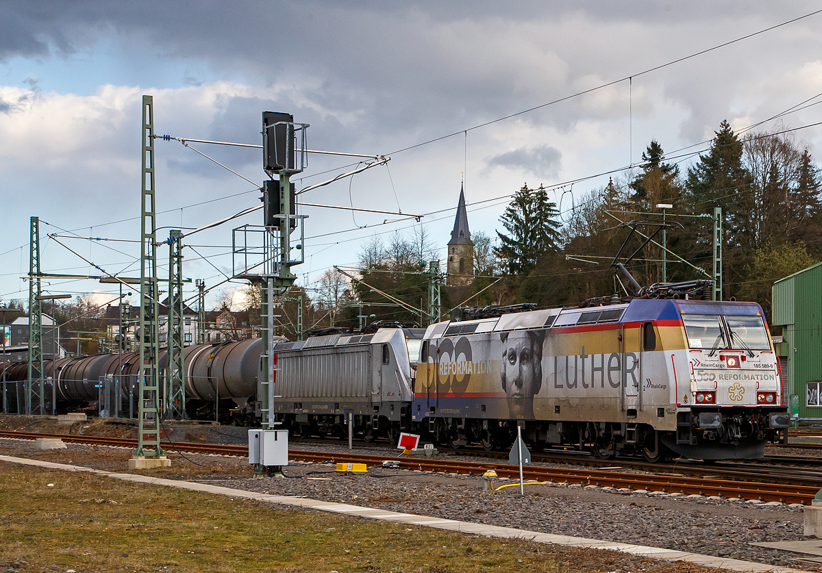 Die RHC 2057 bzw. RheinCargo 185 589-9  500 Jahre Reformation - Luther   (91 80 6185 589-9 D-RHC), ex HGK 2057 (91 80 6185 589-9 D-HGK), f�hrt am 27.03.2021, mit der kalten AKIEM 187 504-6 und einem mit Dieselkraftstoff bzw. leichtes Heiz�l (laut Gefahrstofftafel 30/1202) beladebenen Kesselwagenzug, durch Betzdorf (Sieg) in Richtung K�ln.

Einen lieben Gru� an die beiden netten und gr��enden Lokf�hrer zur�ck, sorry das ich nicht Vorort gegr��t hatte, ich war mit der Positionierung der Lok zwischen den Masten besch�ftigt und hatte es zu Hause erst gesehen.

Die TRAXX F140 AC2 (BR 185.2) wurde 2008 von Bombardier in Kassel unter der Fabriknummer 34210 gebaut, sie hat die EBA-Nummer EBA 03J15D 040. Zulassungen hat die Lok f�r Deutschland, �sterreich und die Schweiz, sie hat auch vier Stromabnehmer. Eigentlicher Eigent�mer ist die AKIEM SAS, die zum 23.04.2020 das Leasinggesch�ft f�r Schienenfahrzeuge von der Macquarie European Rail Limited (Luxembourg), ehemals CBRail �bernommen hat.

Die Lok war bis 2013 war sie an die HGK (H�fen und G�terverkehr K�ln AG) vermietet, ab 2013 nun an die RheinCargo GmbH & Co. KG (RheinCargo) in Neuss, diese ist ein Gemeinschaftsunternehmen HGK und der Neuss-D�sseldorfer H�fen GmbH & Co. KG (NDH), die jeweils zu jeweils 50 % Eigent�mer sind. Insgesamt geh�ren sieben Binnenh�fen mit einem Gesamtumschlag von 29,7 Mio. Tonnen zum Unternehmen.