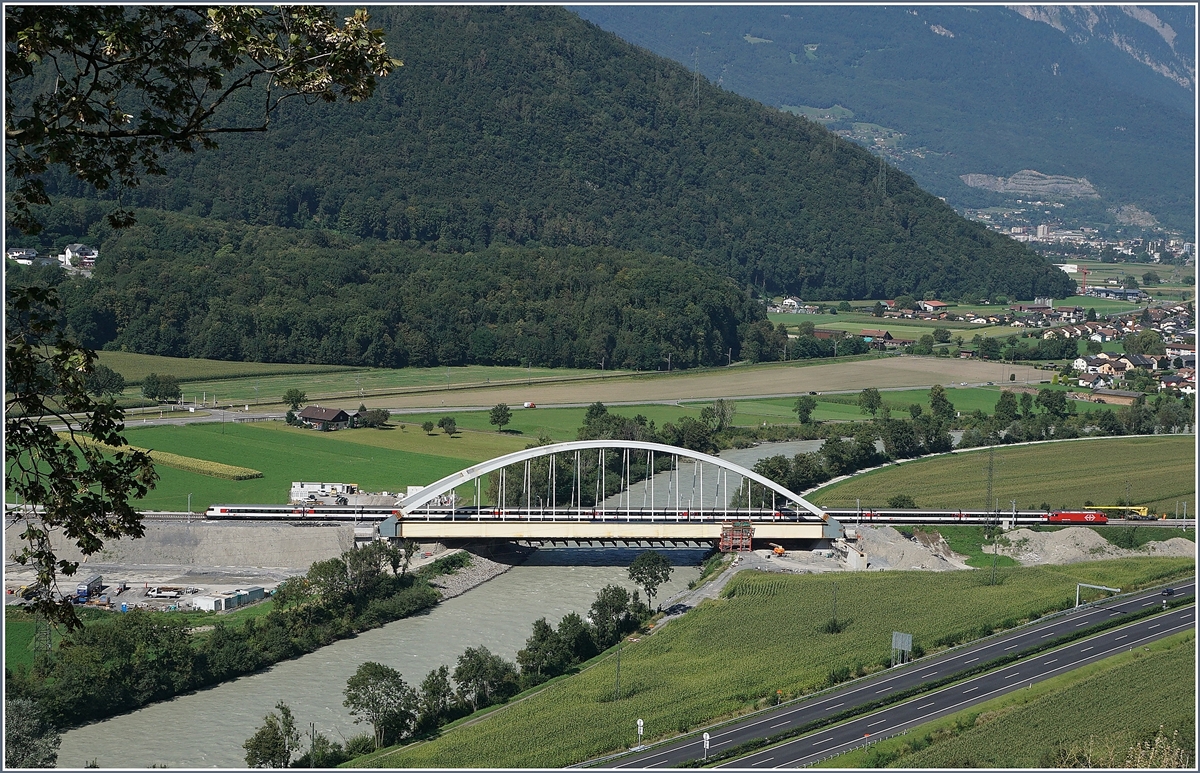 Die Suche nach einem besseren Fotostelle f�r die neue Rhonebr�cke f�hrten mich an Nahe an den sicheren Abgrund; doch von dort hat man eine sch�nen Blick auf die Br�cke und die Rhone-Eben des Chablais. Im Hinterrund ist Monthey zu erkennen, in der Bildmitte liegt Massongex und auch die Fahrplanfeld Strecke 130 (St-Maurice - St-Gingolph) ist zu sehen. Das Gebiet rechts der Rohne geh�rt bereits zum Kanton Waadt, welches eine Re 460 mit dem IR 1816 von Brig nach Gen�ve gerade erreicht hat. 26. August 2016