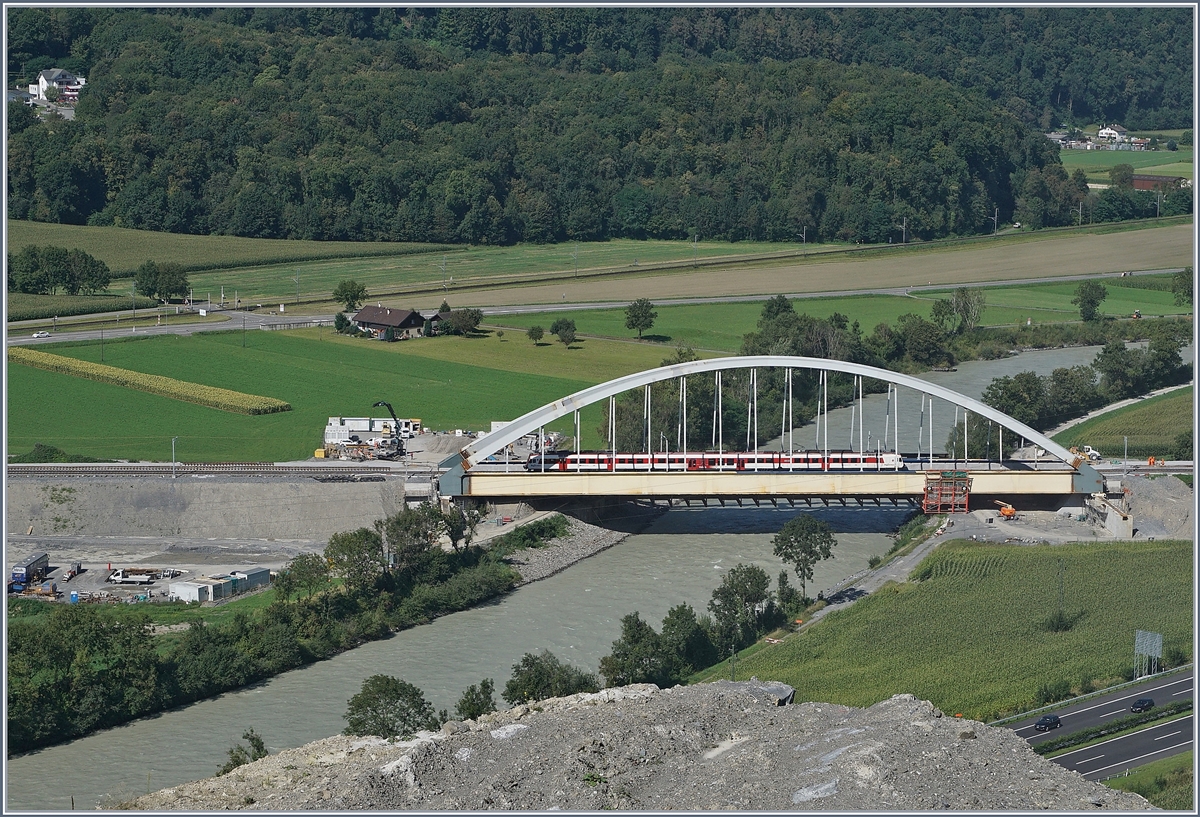 Die Suche nach einem besseren Fotostelle f�r die neue Rhonebr�cke f�hrten mich an Nahe an den sicheren Abgrund. 
Doch Abschrankungen des Kieswerkes beachtend und so auf �ffentlichem Grund bleibend, hat man einen ungef�hrlichen und sch�nen Blick auf die neuen Rhonebr�cke, die demn�chst an ihren definitiven Standort verschoben werden wird. 
Auf dem Bild bef�hrt ein  Walliser Domino  die Br�cke, welcher f�r die seit Fahrplanwechsel teilweise fehlenden Halte der IR als RE zwischen St-Maurice und Aigle verkehrt. 
26. August 2016