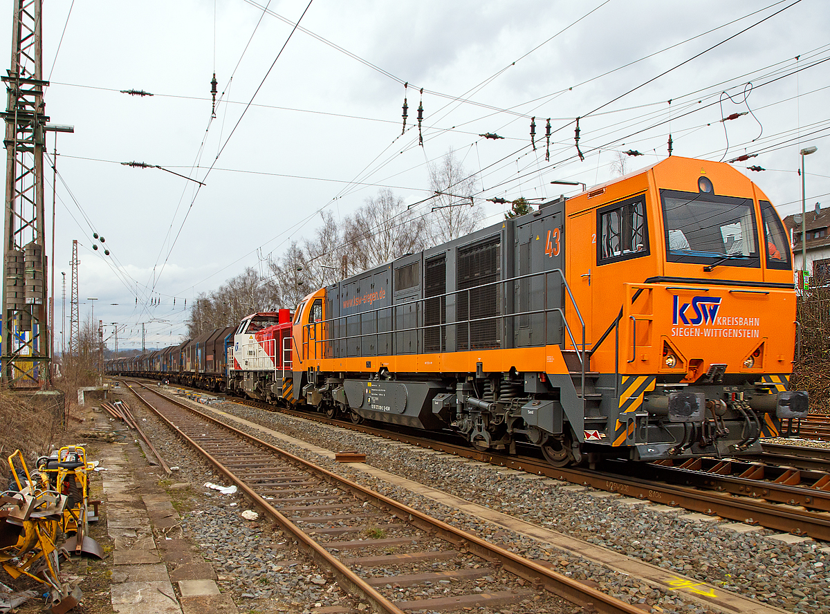 
Ein langer Coilzug fürs Hellertal und eine ungewöhnliche Doppeltracktion.....
Die Kreisbahn Siegen-Wittgenstein (KSW) Lok 43 (92 80 1273 018-2 D-KSW), eine Vossloh MaK G 2000 BB und die Lok 47 (92 80 1271 027-5 D-KSW), ex D 2 der HFM, eine Vossloh G 1000 BB, rauschen am 17.03.2017 mit einem langen Coilgüterzug durch Kreuztal in Richtung Siegen. 

Über Siegen, Betzdorf/Sieg und Herdorf geht es nach Neunkirchen-Salchendorf zum Pfannenberg. Wobei in Herdorf der Zug geteilt und die Lok meist gewechselt wird. 

Die KSW holt täglich Coils aus dem Duisburger Hafen ins südliche Siegerland. Auf einem solchen Drehgestell-Flachwagen mit Teleskophauben der Gattung Shimmns² befinden sich jeweils 4 Coils (kaltgewalztes Blech aufgerollt zu Rollen). Wenn man es über die Straße fahren wöllte bräuchte man für jeden Wagon gleich vier LKW´s. Zudem kann man einen jährlichen Anstieg der Tonnagen beobachten.

Die Doppeltracktion ist wohl auf der Ruhr-Sieg-Strecke auch nötig, die Steigung im Sauerland beträgt zwar nur 12 ‰, ist aber sehr lang und kurvenreich.  Daher sind häufige Geschwindigkeitswechsel notwendig.

Noch heute werden schwere Güterzüge auf der Ruhr-Sieg-Strecke in Richtung Süden zwischen Lennestadt-Altenhundem und Welschen Ennest mit einer zusätzlichen Lok nachgeschoben. Diese fährt danach wieder zurück nach Lennestadt-Altenhundem. Vor der Elektrifizierung der Ruhr-Sieg-Strecke wurden fast alle Güterzüge bis Welschen Ennest nachgeschoben. Seltener hatten und haben Güterzüge ab Kreuztal bis Welschen Ennest diese Unterstützung.
