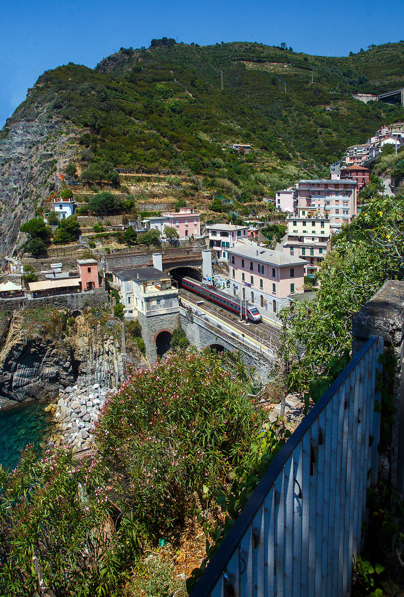 Ein Trenitalia Frecciargento ETR 485 (Pendolino) fährt am 21.07.2022 durch den Bahnhof Riomaggiore in Richtung La Spezia bzw. Pisa.

Riomaggiore ist das südlichste der fünf Dörfer der Cinque Terre (Fünf Ortschaften) und verfügt, wie die anderen Dörfer, über einen Bahnhofan der Bahnstrecke Pisa–Genua, die den Ort mit den Nachbardörfern und mit La Spezia und Sestri Levante verbindet. Der Bahnhof von Riomaggiore liegt am nordwestlichen Ortsrand weitgehend im Tunnel, nur drei Wagenlängen befinden sich unter freiem Himmel. Der Ortskern wird mittels eines in einem Eisenbahntunnel verlaufenden Fußpfades angebunden. Man kann aber auch wie wir hier den Weg/später Pfad über den Bahnhof nehmen, dann muss man aber später Treppen laufen, was für die Cinque Terre sehr normal ist.

Auf ein Entzerren habe ich hier bewusst verzichtet.
