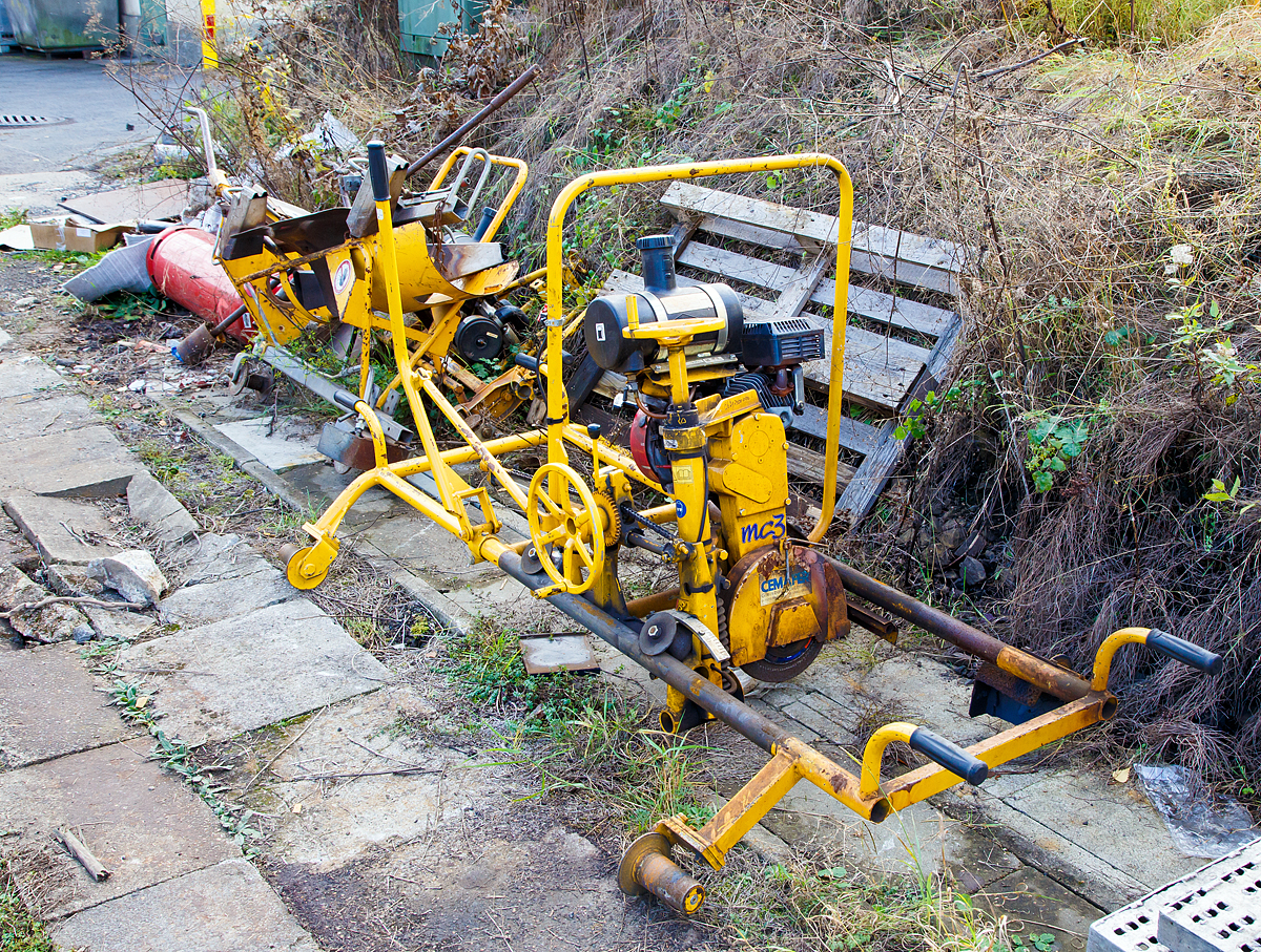 
Eine CEMAFER / Geismar Weichenentgratungsmaschine Typ MC3 (Baujahr 2015) abgelegt am 30.10.2016 in Kreuztal.

Das Gerät hat eine stufenlose Horizontal- und Vertikalverstellung und stufenlose Neigungsverstellung. Das Gesamtgewicht beträgt 87 kg, mittels der Handgriffe wird es von 2 Mann zur Schleifstelle getragen und aufs Gleis/Weiche abgesetzt.

Der Antrieb der Schleifspindel erfolgt durch einen luftgekühlten 1-Zylinder 4-Takt OHV Benzinmotor, vom Typ HONDA GX 200 H.
Technische Daten des Motors:
Hubraum:   196 cm³
Leistung:  4.1 kW (5.5 PS) / 3 600 U/min
Max. Dauerleistung: 3.3 kW (4.4 PS) / 3 000 U/min
Benzinverbrauch bei Dauerleistung: 1.7 L/h
Trockengewicht:   16 kg