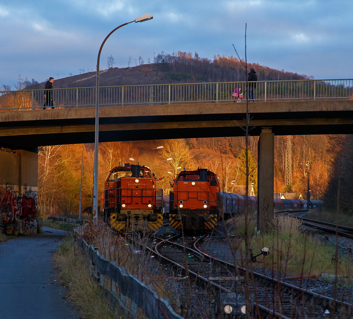 Freien Grunder Eisenbahn (KSW NE447 / DB-Nr. 9275) der Kreisbahn Siegen-Wittgenstein am spätem Nachmittag des 24.11.2021 in Herdorf:
Links fährt nun die die KSW 44 (92 80 1271 004-4 D-KSW) die MaK G 1000 BB durch den Rbf und weiter in Richtung Neunkirchen-Salchendorf. Rechts steht die KSW 42 (92 80 1277 902-3 D-KSW), eine Vossloh MaK G 1700 BB, mit einem Übergabe-Güterzug (von Herdorf zum Rbf Kreuztal) zur Abfahrt bereit.
