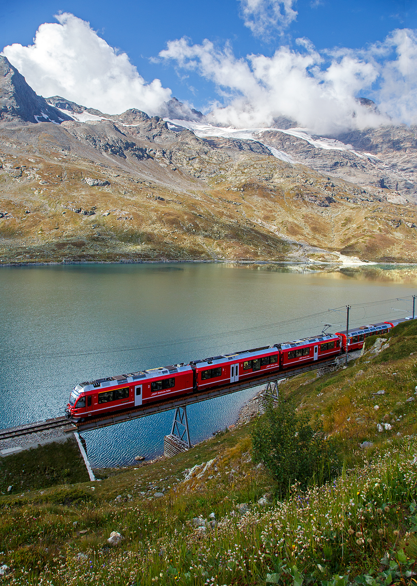 Leider unter einer leidigen Fotowolke....
Der RhB ALLEGRA-Zweispannungstriebzug (RhB ABe 8/12) 3504  Dario Cologna  fährt am 06.09.2021, mit dem Bernina Express nach Tirano, bei Ospizio Bernina über die 46 m lange „Am See Brücke“ am Lago Bianco entlang. 

Hier oben beim Berninapass bzw. an der Staumauer des Lago Bianco befindet sich auch zugleich die Wasserscheide zwischen Donau und Po. In Richtung Tirano fließ das Wasser in den Po und somit ins Mittelmeer, in Richtung St.Moritz fließ das Wasser in die Donau und somit ins Schwarze Meer.
