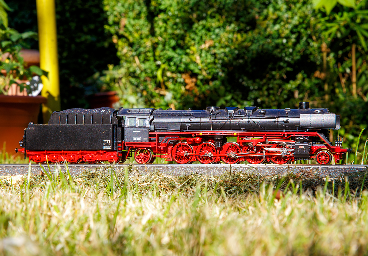 Mein Liliput H0-Modell (AC mit Sound) der DB Güterzuglok 45 010 (045 010-6), am 03.07.2018 auf einem kurzen Gleis in Herdorf. 

Von den insgesamt 28 gebauten Lokomotiven dieser Baureihe blieb nur die 45 010 erhalten. Sie wurde aber leider 2005 bei dem Brand des Verkehrsmuseums Nürnberg stark beschädigt. 2012 wurde die Lokomotive im Dampflokwerk Meiningen wieder optisch und rollfähig als museales Ausstellungsfahrzeug aufgearbeitet. Sie steht heute im Depot des VM Nürnberg in Lichtenfels, leider nicht frei zugänglich. So will ich mit diesem Bild von dem Modell die Baureihe gerne näher ausführen:

Die Lokomotiven der Baureihe 45 waren Einheits-Güterzuglokomotiven der Deutschen Reichsbahn, sie waren die stärksten Dampflokomotiven, die in Deutschland zum Einsatz gekommen sind.

Die Prototypen wurden 1936 und 1937 durch die Firma Henschel gebaut. Nach den ersten beiden Maschinen wurden ab 1940 weitere 26 Exemplare geliefert. Der dritte Auftrag über weitere 103 Maschinen wurde 1941 wieder storniert, da nach Ausbruch des Zweiten Krieges der Bau der einfacheren Kriegslokomotiven favorisiert wurde.


Ursprünglich waren diese schweren Güterzuglokomotiven für die Beschleunigung des Güterzugverkehrs auf Hauptstrecken gedacht. Sie sollte die G 12 ersetzen und die Baureihe 44 nach oben ergänzen. Sie hatten deshalb wie die Baureihe 41 einen größeren Treib- und Kuppelraddurchmesser von 1.600 mm, als die anderen Einheits-Güterzuglokomotiven mit 1.400 mm. Ihre zulässige Höchstgeschwindigkeit lag deshalb statt bei 80 km/h bei 90 km/h.

Weitere Anforderungen waren, dass 1.200 Tonnen in der Ebene noch mit 80 km/h und 1.000 Tonnen auf fünf Promille Steigungen noch mit 60 km/h bewegt werden sollten. Zudem sollten Kurven mit Radien ab 140 Metern noch befahrbar sein und Weichen 1:7 zwanglos durchfahren werden können. Dank des vorderen Krauss-Helmholtz-Lenkgestells war der feste Achsstand kleiner als bei der parallel zu ihr entwickelten Baureihe 06, so dass Weichenstraßen und Gleisbögen besser durchfahren werden konnten.

Die Firmen Henschel, Krupp und Schwartzkopff reichten Entwürfe ein, ausgewählt wurde die Dreizylinder-Maschine von Henschel mit 20 bar Kesseldruck. Als Tender kam der 2'3 T 38 zum Einsatz. Baugleich mit der Baureihe 06 waren der Kessel und der Aufbau der Dampfmaschine. Die Außenzylinder der Baureihe 45 wurden nach demselben Modell gegossen wie die der Baureihe 06 und Baureihe 41.

Die beiden Musterlokomotiven lieferte Henschel im November 1936 und im Juni 1937 mit den Fabriknummern 22 805 und 22 806 ab. Weitere 26 Serienmaschinen wurden erst 1940 (45 003 – 45 005) und 1941 (45 006 – 45 028) geliefert. Der Grund war der für den Einsatz der Loks zwingend erforderliche, jedoch nur schleppend erfolgte Ausbau der Hauptstrecken auf 20 Tonnen Achsfahrmasse und der Kriegsbeginn, durch den hochwertiger Zugverkehr zugunsten der Massenproduktion von Kriegsloks aufgeben werden musste.

Die Lokomotiven waren zuerst im Bw Mannheim (45 001 und 45 002), alle anderen im Bw Würzburg beheimatet, wohin später die Prototypen umgesetzt wurden. Die Loks wurden im schweren Eilgüterzugdienst und im Schnellzugdienst eingesetzt. Sie waren mit 90 km/h Höchstgeschwindigkeit im fränkischen Hügelland und wegen ihrer Laufruhe auf Grund ihres Dreizylindertriebwerks dazu in der Lage, die Baureihe 01 zu vertreten. Genau wie bei der Baureihe 06 gab es bei der Baureihe 45 recht schnell Probleme mit dem überdimensionierten Kessel. Seine 7.500 Millimeter Rohrlänge führte zu vielen Schäden. 1942 musste der Kesseldruck auf 16 bar reduziert werden. 

Im Mai 1945 waren nur noch drei Loks einsatzfähig. Der Rest stand mit schadhaften Kesseln und mit Kriegsschäden in den westlichen Besatzungszonen. Nur die 45 024 befand sich mit Kriegsschäden auf dem Gebiet der Sowjetischen Besatzungszone und verblieb bei der Deutschen Reichsbahn, Teile von dieser Maschine, wie Außenzylinder, Schleppradsatz und hinteres Rahmenteil, leben heute noch in der 18 201.

DB-Baureihe 45
Nach dem Krieg zeigten sich recht bald Kesselschäden, die eine Herabsetzung des Kesselüberdrucks auf 16 bar notwendig machten. Ab 1950 wurden deshalb mehrere Maschinen der Deutschen Bundesbahn mit einem Stehkessel mit Verbrennungskammer und einem mechanischen Rostbeschicker ausgestattet. Die Fahrzeuge mit den Betriebsnummer 45 010, 45 016, 45 019, 45 021 und 45 023 wurden neu mit geschweißten Kesseln und Stoker-Einrichtungen versehen. 1968 besaß die Deutsche Bundesbahn noch drei Exemplare, die als Brems- und Versuchsloks beim Bundesbahnzentralamt in München (45 023) und Minden (45 010, 45 019) eingesetzt wurden.

Diese Baureihe galt zunächst ähnlich der Baureihe 06 wegen des anfälligen Kessels als Fehlkonstruktion, doch durch die Neubekesselung samt mechanischer Rostbeschickung (Stoker) wurden die wahren Qualitäten der Lok sichtbar. Die 45 010 und 45 019 wurden in ihren letzten Jahren neben dem Dienst als Bremslokomotive für das Bundesbahnzentralamt immer wieder in schweren Güterzugdiensten eingesetzt, mit denen Loks der Baureihe 44 Probleme hatten.

Die Fahrzeuge waren mit Schlepptendern der Bauart 2'3 T 38 ausgestattet. Diejenigen mit Stoker-Einrichtungen hatten Schlepptender der Bauart 2'3 T 29 Stoker.

Von den insgesamt 28 gebauten Lokomotiven dieser Baureihe blieb zuletzt nur die 45 010 erhalten. Am Abend des 17. Oktober 2005 wurde sie bei einem Großbrand im Lokschuppen des Verkehrsmuseums Nürnberg stark beschädigt. 

TECHNISCHE DATEN:
Spurweite:  1.435 mm (Normalspur)
Bauart:  1'E1' h3
Gattung:  G 57.18 (umstellbar auf G 57.20)
Länge über Puffer:  25.645 mm
Leergewicht:  112,3 t (Neubaukessel)
Dienstgewicht mit Tender:  198,2 t (bei Neubaukessel, mit vollen Vorräten)
Höchstgeschwindigkeit:  90 km/h
Indizierte Leistung: 2.059 kW / 2.800 PS
Anfahrzugkraft: ca. 287 kN (bei 20 bar Kesseldruck der Ursprungsausführung), ca. 230 kN (bei 16 bar Kesseldruck mit Neubaukessel)
Treibraddurchmesser:  1.600 mm
Laufraddurchmesser vorn:  1.000 mm
Laufraddurchmesser hinten:  1.250 mm
Zylinderanzahl:  3
Zylinderdurchmesser:  520 mm
Kolbenhub:  720 mm
Kesselüberdruck: 16 bar (Neubaukessel)
Tender:  2'3 T 38 (oder  2'3 T 29 Stoker)
Wasservorrat: 38,0 m³ (oder 29,0 m³) 
Kohlevorrat: 10 t (oder 12 t)