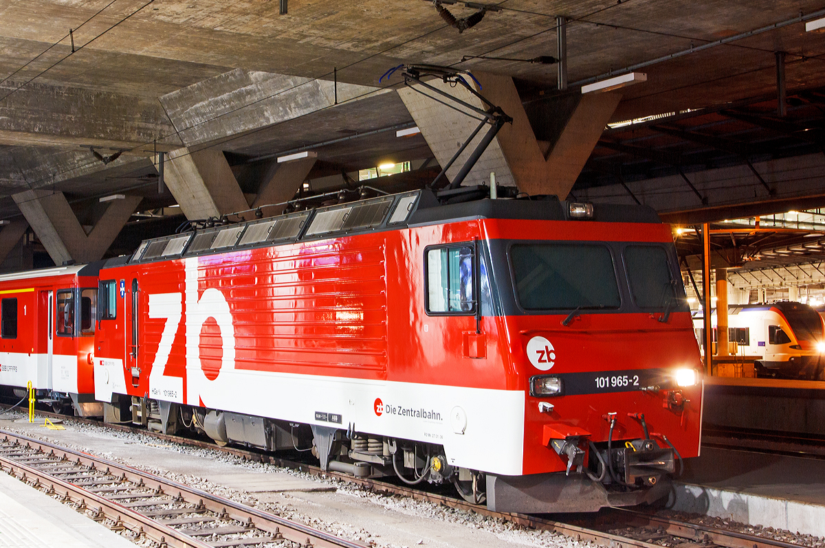 
Nachtschwärmereien - Die zb (Zentralbahn)  HGe 4/4 II - 101 965-2 „Lungern“  ist am 29.09.2012 (4:40 Uhr) mit einem Zug der zb im Bahnhof Luzern abgestellt. 

Die HGe 4/4 II 101 965-2 „Lungern“  wurde SLM (Schweizerische Lokomotiv- und Maschinenfabrik) in Winterthur 1990 unter der Fabriknummer 5399 gebaut, der elektrische Teil ist von ABB.

Die HGe 4/4 II - 101 ist eine schmalspurige (1.000 mm) gemischte Zahnrad- und Adhäsions-Lokomotive. Eine erste Serie von fünf Lokomotiven wurde gemeinsam von der Furka-Oberalp-Bahn (FO) sowie von der SBB für die Brünigbahn, die heute zur Zentralbahn (zb) gehört, beschafft. Da sich dieser Lokomotivtyp bewährte, wurden weitere elf Lokomotiven bestellt, und schließlich gab auch noch die Brig-Visp-Zermatt-Bahn (BVZ) fünf Loks in Auftrag.

Die HGe 4/4 II bespannt vor allem schwere Personenzüge, zum Teil im Pendelzugbetrieb. Bei der Zentralbahn bespannte sie bis 2012 alle Schnellzüge von Meiringen nach Luzern, bei der Matterhorn Gotthard Bahn die Züge des Glacier-Express. Weiter führen die Loks Pendelzüge Brig–Visp–Zermatt und seit der Eröffnung des Tunnels nach Engelberg Pendelzüge Luzern–Engelberg. Außerdem werden aushilfsweise Autopendelzüge durch den Furkatunnel geführt. Schließlich gehören neben weiteren Personenzügen auch diverse Güterzüge Visp–Zermatt sowie bis 2013 Disentis–Sedrun (NEAT-Baustelle) zum Aufgabengebiet.

Konstruktion:
Der Lokomotivkasten ist ein Stahlblechkasten mit gesickten Seitenwänden. Die asymmetrische Frontscheibe aus beheizbarem Verbundglas verbessert die Sicht für den Lokomotivführer. Die drei Dachelemente sind aus Aluminium. Die Pufferkräfte werden über Verstrebungen auf den ganzen Kasten übertragen, weshalb auf seitliche Maschinenraumöffnungen verzichtet werden musste. Der gesamte Kasten hat ein Gesamtgewicht von nur 5,9 Tonnen. Er kann ohne bleibende Deformation eine zentrale Druckkraft von 1000 kN aufnehmen.

Die Drehgestelle sind als geschweißte Hohlträgerkonstruktion mit zwei Längsträgern und einem kräftigen mittleren Querträger sowie zwei Kopftraversen ausgeführt. Sie haben einen Achsstand von 2980 mm, und die Flexicoilfedern stützen den Kasten auf die seitlich an die Längsträger angeschweißten Federwannen. Die Zug- und Druckkräfte werden durch seitlich angeordnete Stangen mit Sphärolastiklagern übertragen. Wegen des kurzen Achsstands sind die Fahrmotoren oberhalb des Drehgestellrahmens angebracht.

Für den Antrieb wurde erstmals der Differentialantrieb eingebaut, der es ermöglicht, im Zahnstangenbetrieb auch einen Anteil der Zugkraft über den Adhäsionsantrieb aufzubringen. Dies setzt wiederum eine Schlupfbegrenzung im Differentialgetriebe voraus, um ein Schleudern oder Gleiten der Räder zu verhindern. Da die zweilamellige Abtzahnstange (System Abt) der FO nicht die gesamte Zugkraft aufnehmen kann, ist die Mithilfe des Adhäsionsantriebs notwendig; dieser übernimmt einen Drittel der Zugkraft. Hätte sich der Antrieb nicht bewährt, wäre es zumindest am Brünig mit der Riggenbachzahnstange möglich gewesen, auf einen abkuppelbaren Adhäsionsantrieb zu wechseln. Dies war aber nicht notwendig, da das Differentialgetriebe zur vollen Zufriedenheit funktionierte.

Bremssysteme:
Dank der elektrischen Rekuperationsbremse ist eine gleichmäßige Beharrungsbremse bei der Talfahrt möglich.
Daneben ist eine normale automatische Druckluftbremse eingebaut, welche auch als Bremssystem I bezeichnet und im Regelbetrieb zum Halten des Zuges verwendet wird. Sie ist als Klotzbremse ausgeführt.
Weiterhin ist noch das Bremssystem II installiert, welches für Zahnradbahnen vorgeschrieben ist und es ermöglichen soll, den Zug nur mit Hilfe der Lokomotive im Zahnstangenabschnitt zum Halten zu bringen, wenn das erste Bremssystem ausfallen sollte. Dieses ist als federspeichergestütztes Bandbremssystem ausgelegt, welches direkt auf das Zahnrad wirkt. Bei Einsatz dieser Bremse treten enorme Kräfte auf, welche nur unter Kontrolle sind, wenn die Anhängelast bei der Talfahrt nicht zu groß ist.
Schließlich ist eine direkt wirkende Rangierbremse vorhanden, die sich der Bremsklötze des Bremssystems I bedient.
Die Lokomotive hat keine Handbremse, sondern wird mit Federspeicherbremsen gesichert.

Technische Daten, der HGe 4/4 II der zb (Brünigbahn), die der FO und BVZ weichen ab:
Spurweite: 1.000 mm
Achsformel: Bo'Bo'
Dienstgewicht: 63 t 
Achslast: 16 t
Länge über Puffer: 14'800 mm 
Höchstgeschwindigkeit Adhäsion: 100 km/h
Höchstgeschwindigkeit Zahnrad: 40 km/h
Stromsystem: 15 kV 16.7 Hz 
Anzahl der Motoren: 4
Antrieb: Gelenkwelle
Antrieb Zahnrad: Differentialantrieb
Zahnradsystem: 	Riggenbach 
Stundenleistung: 1.932 kW
Dauerleistung: 1.875 kW
Anfahrzugkraft: 230 kN (Adhäsion) / 280 kN (Zahnrad)
Anzahl Bremssysteme: 4
Bremsen: Rekuperation, Klotz, Federspeicher, Bandbremse
Anhängelast: 170 t (120 ‰) 
