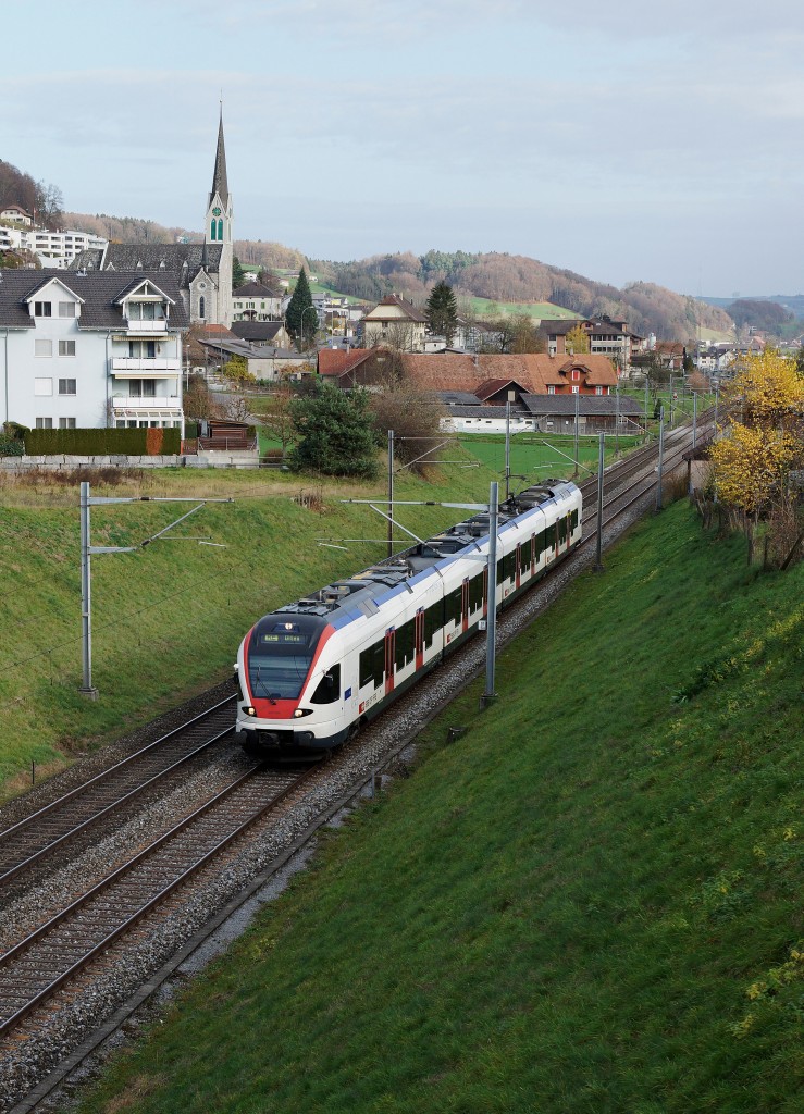 SBB: RE mit Triebzug 523 FLIRT nach Olten beim Passieren der Kirche Wauwil am 15. November 2015.
Foto: Walter Ruetsch